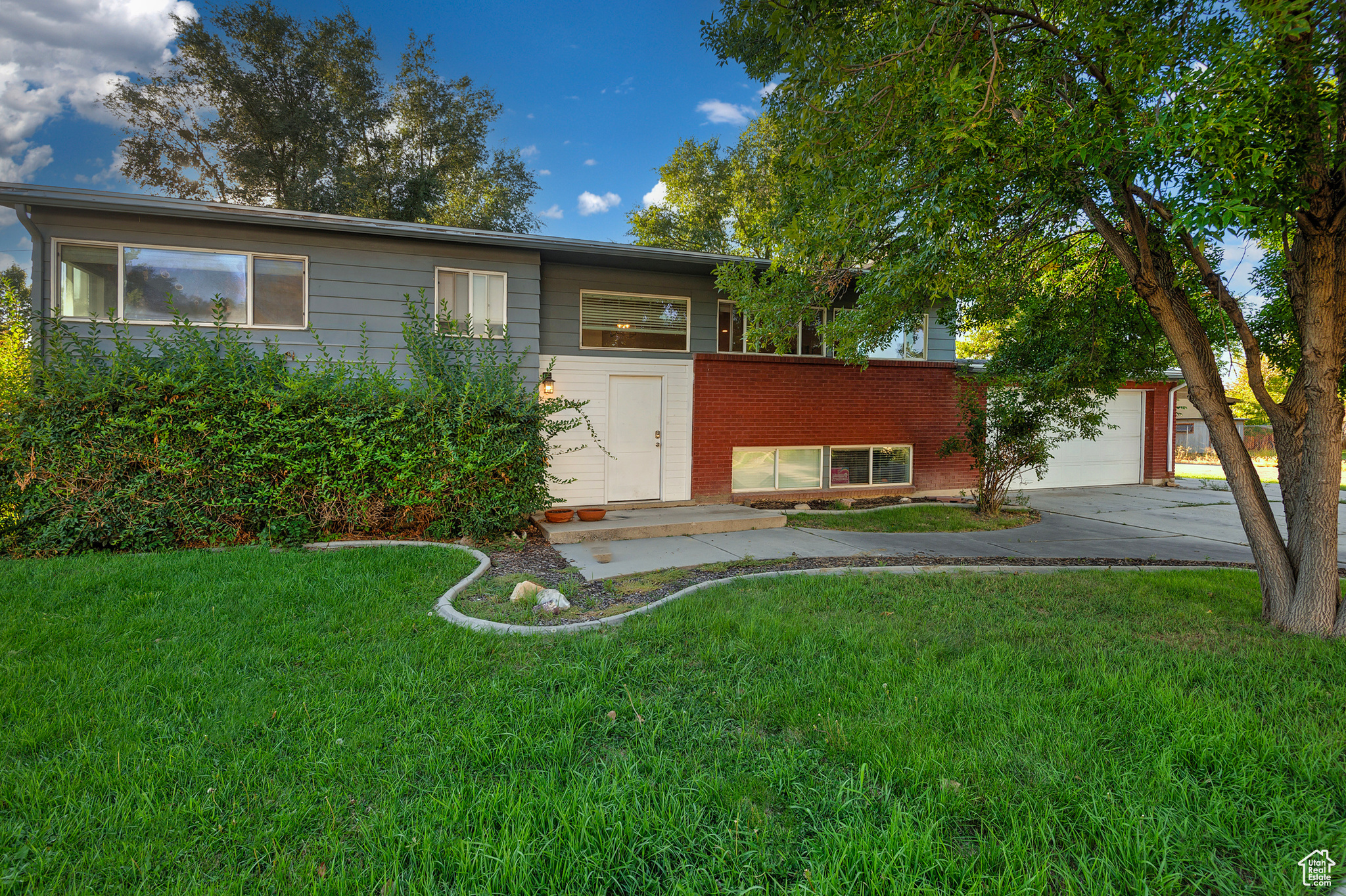 View of front of property featuring a front yard, an attached garage, brick siding, and driveway