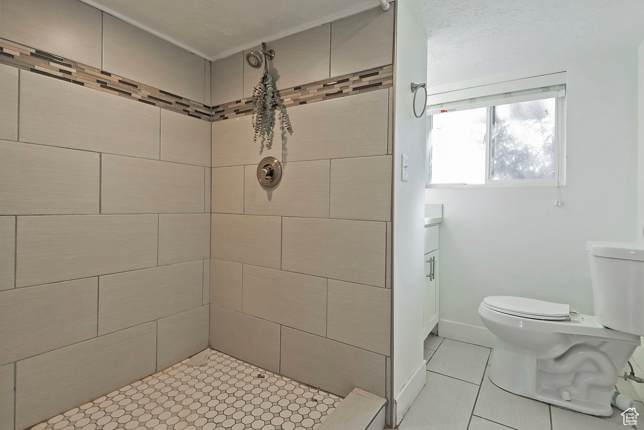 Full bathroom featuring tiled shower, toilet, and baseboards