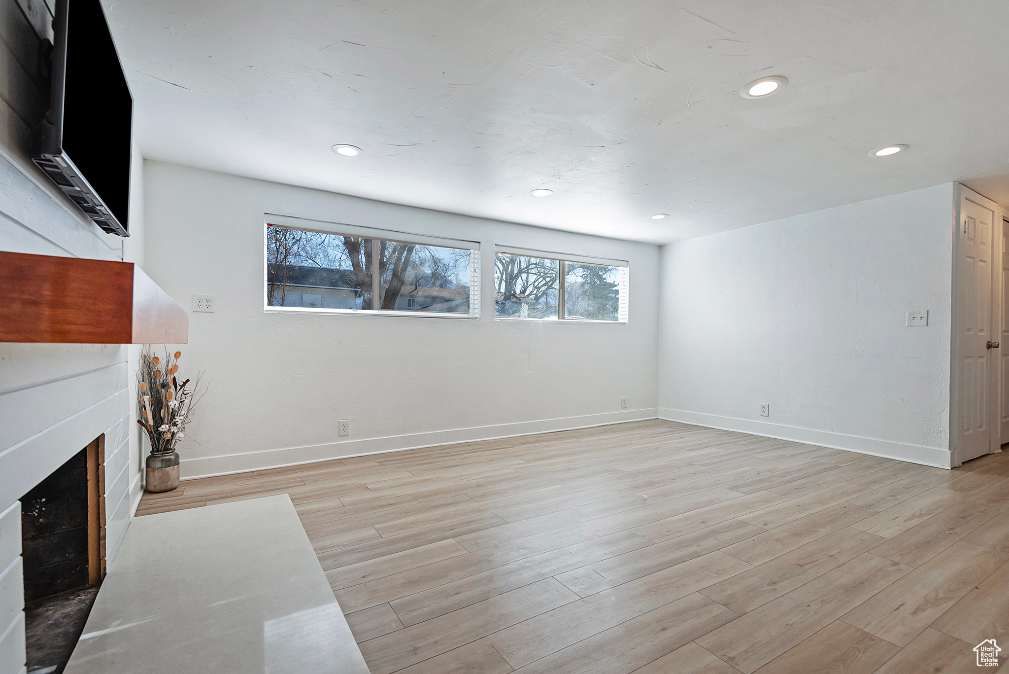 Living area with a fireplace, recessed lighting, light wood-style floors, and baseboards