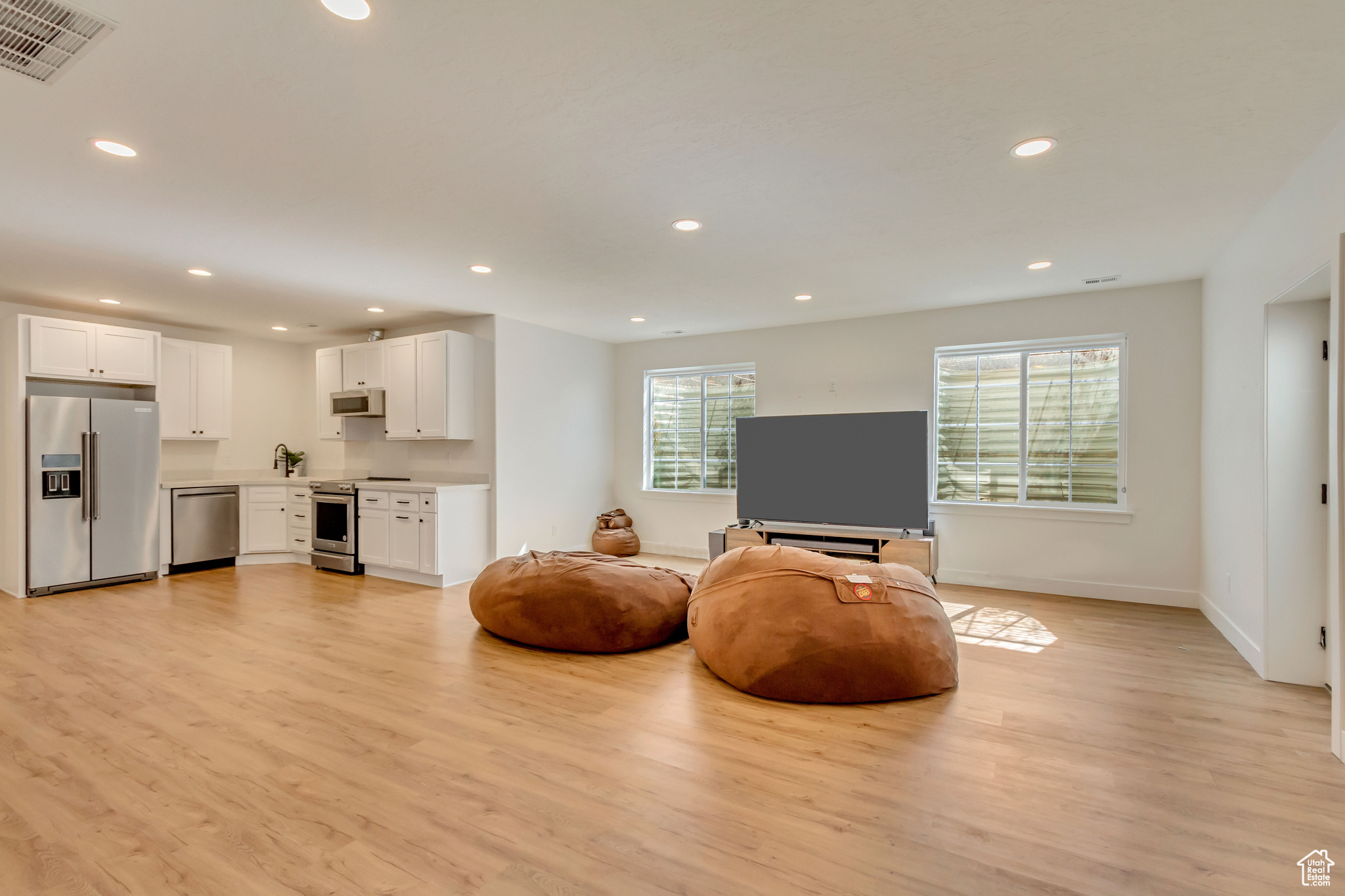 Living area with visible vents, recessed lighting, light wood-type flooring, and baseboards