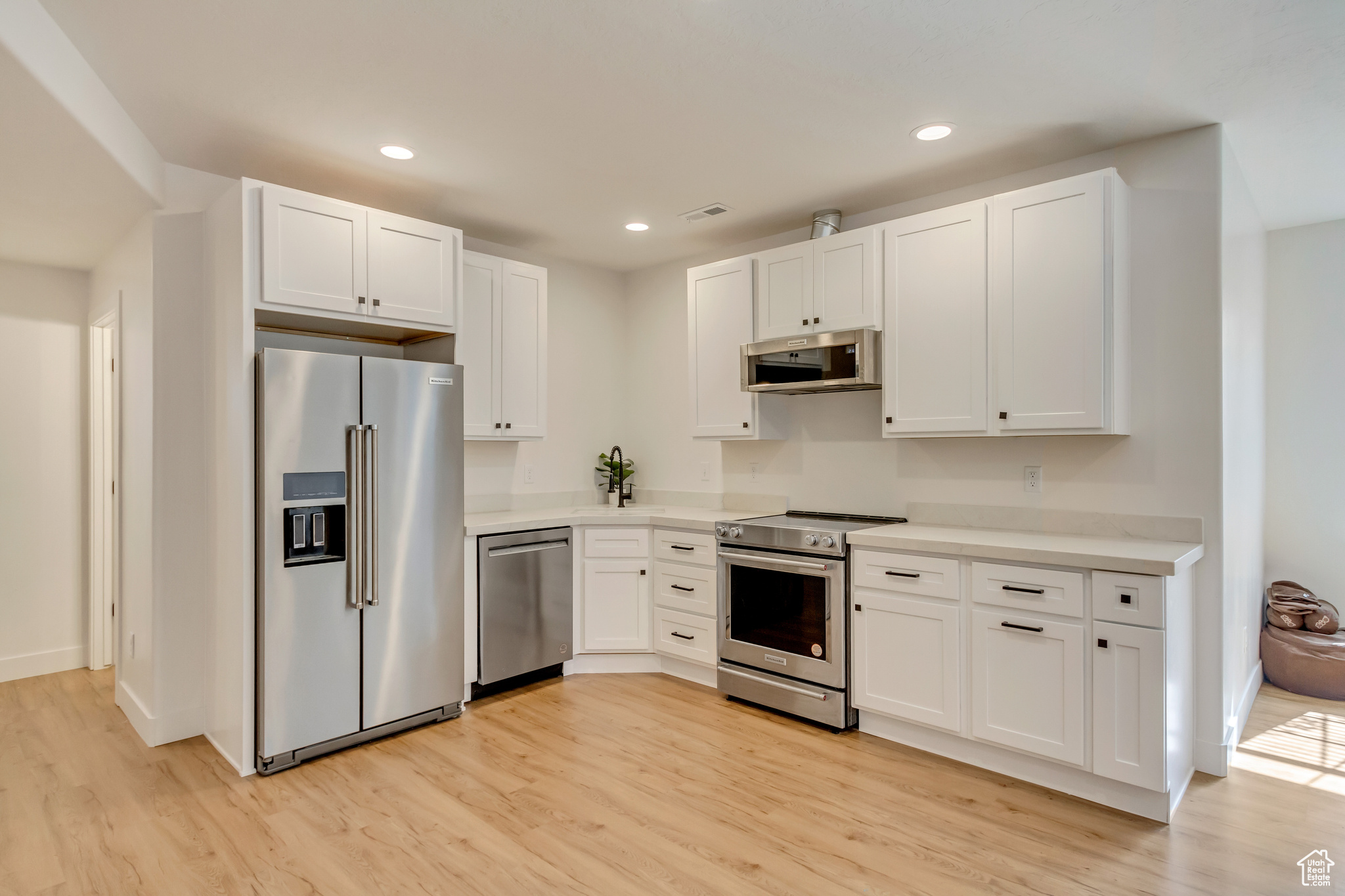 Kitchen featuring white cabinets, light wood finished floors, and stainless steel appliances