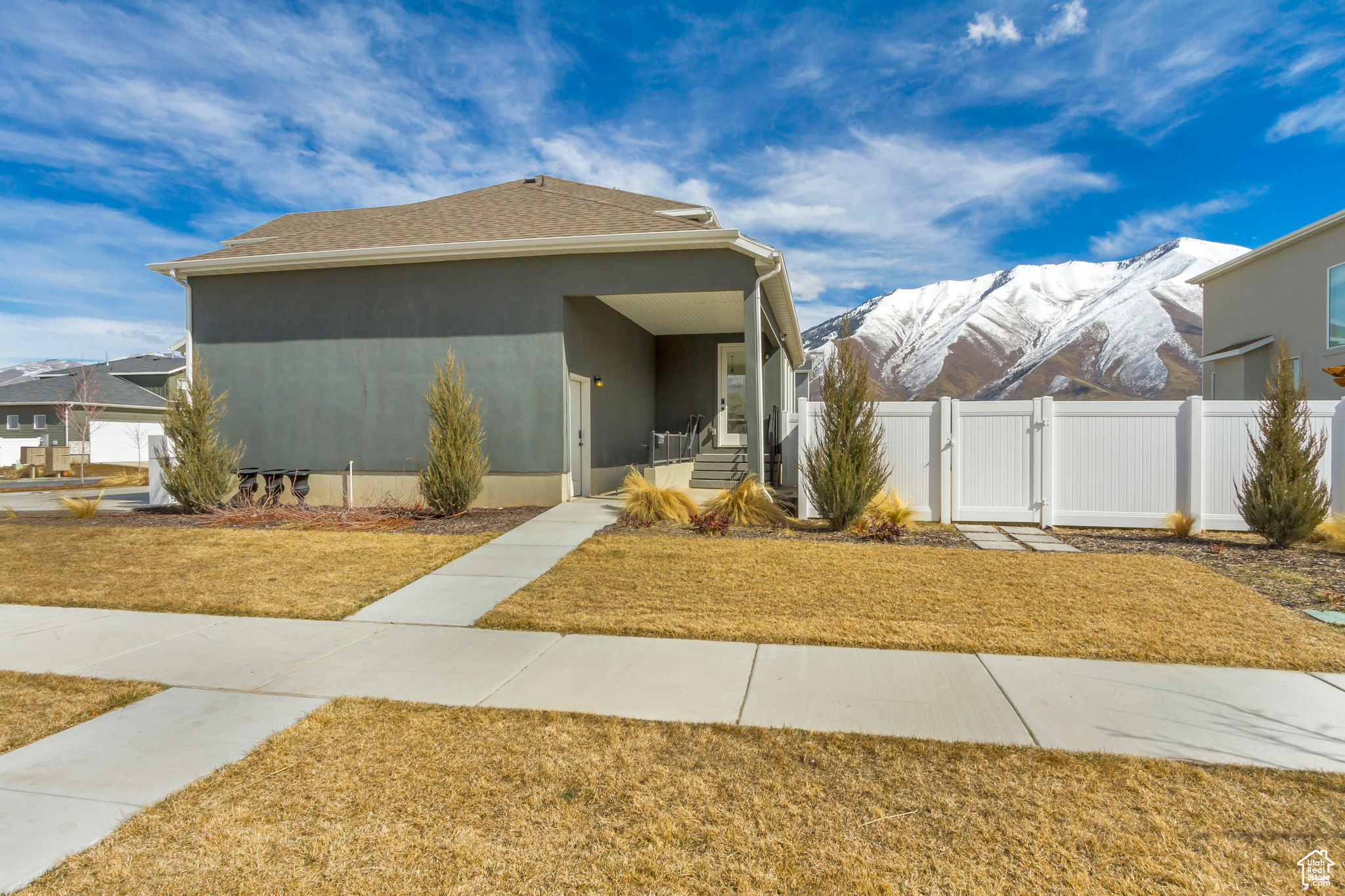 View of front of home with stucco siding, a front lawn, a gate, fence, and a mountain view