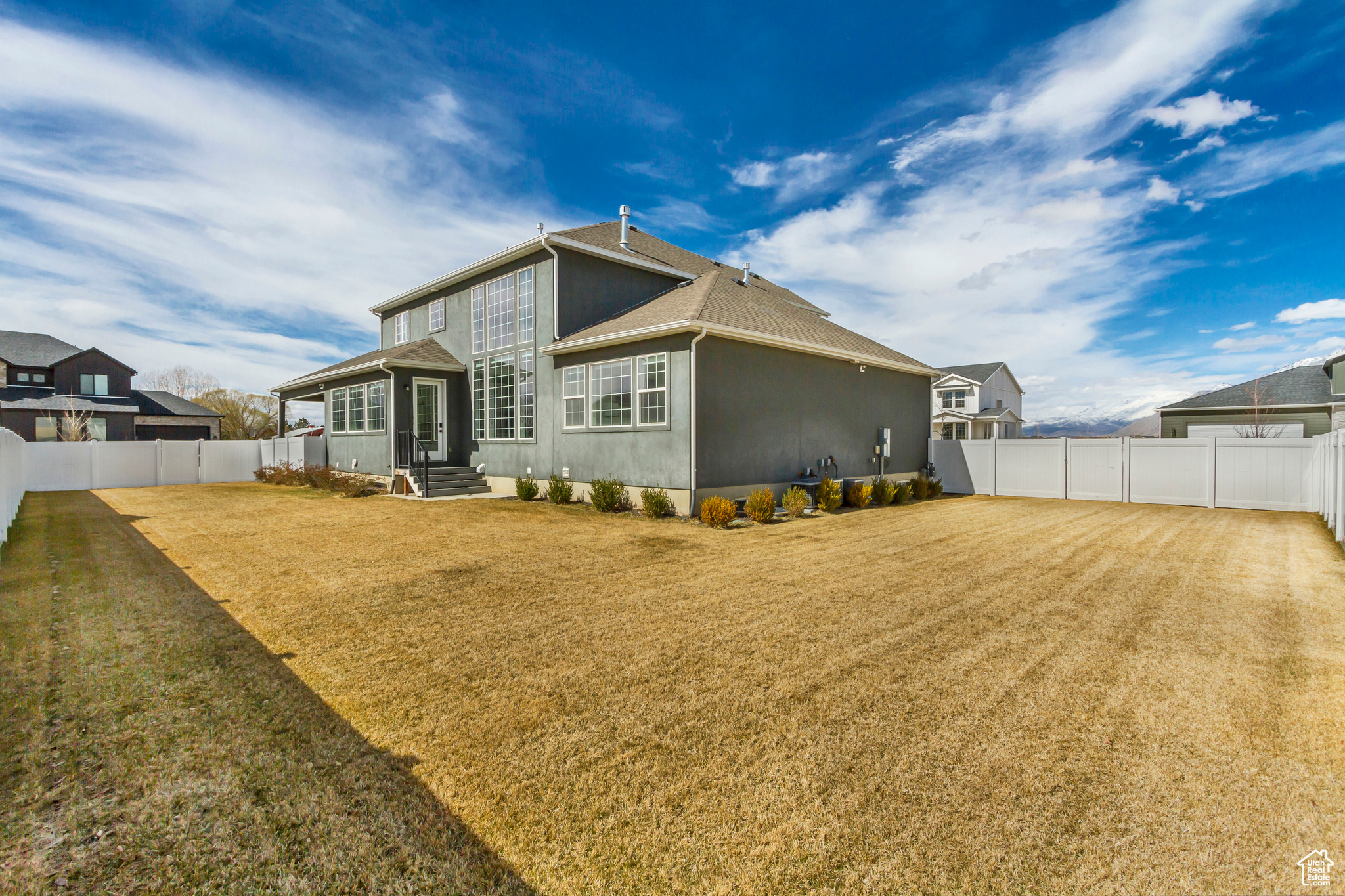 Back of property with a yard, stucco siding, entry steps, and a fenced backyard