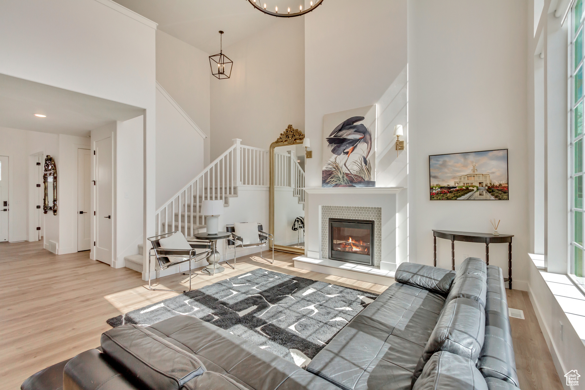 Living room with stairway, a fireplace, a high ceiling, an inviting chandelier, and wood finished floors