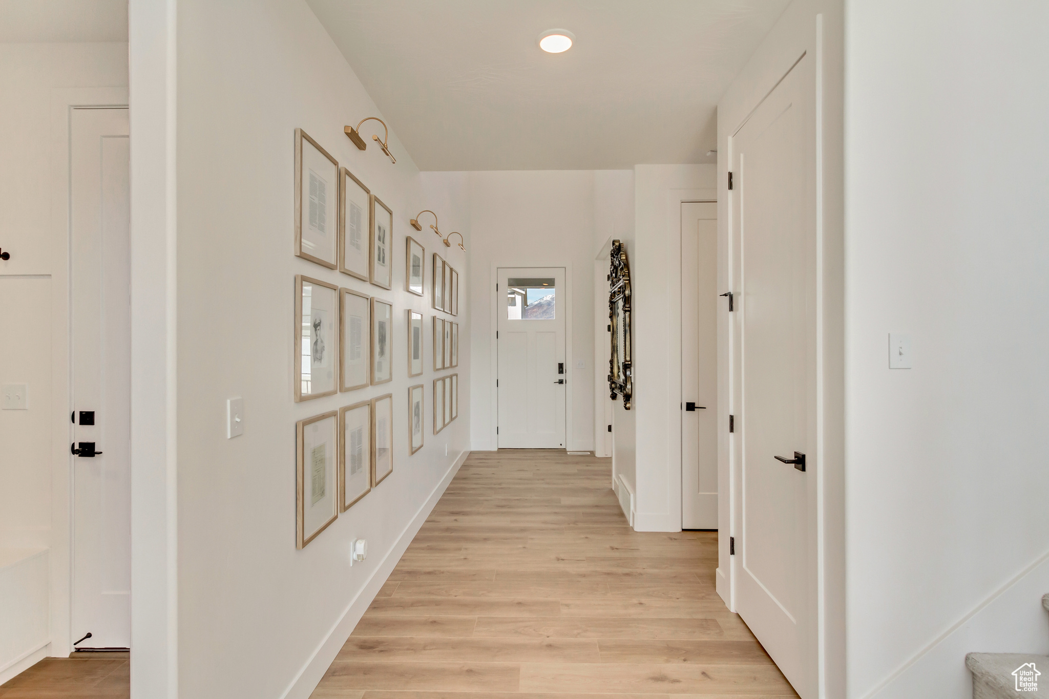 Corridor with light wood finished floors, stairway, and baseboards