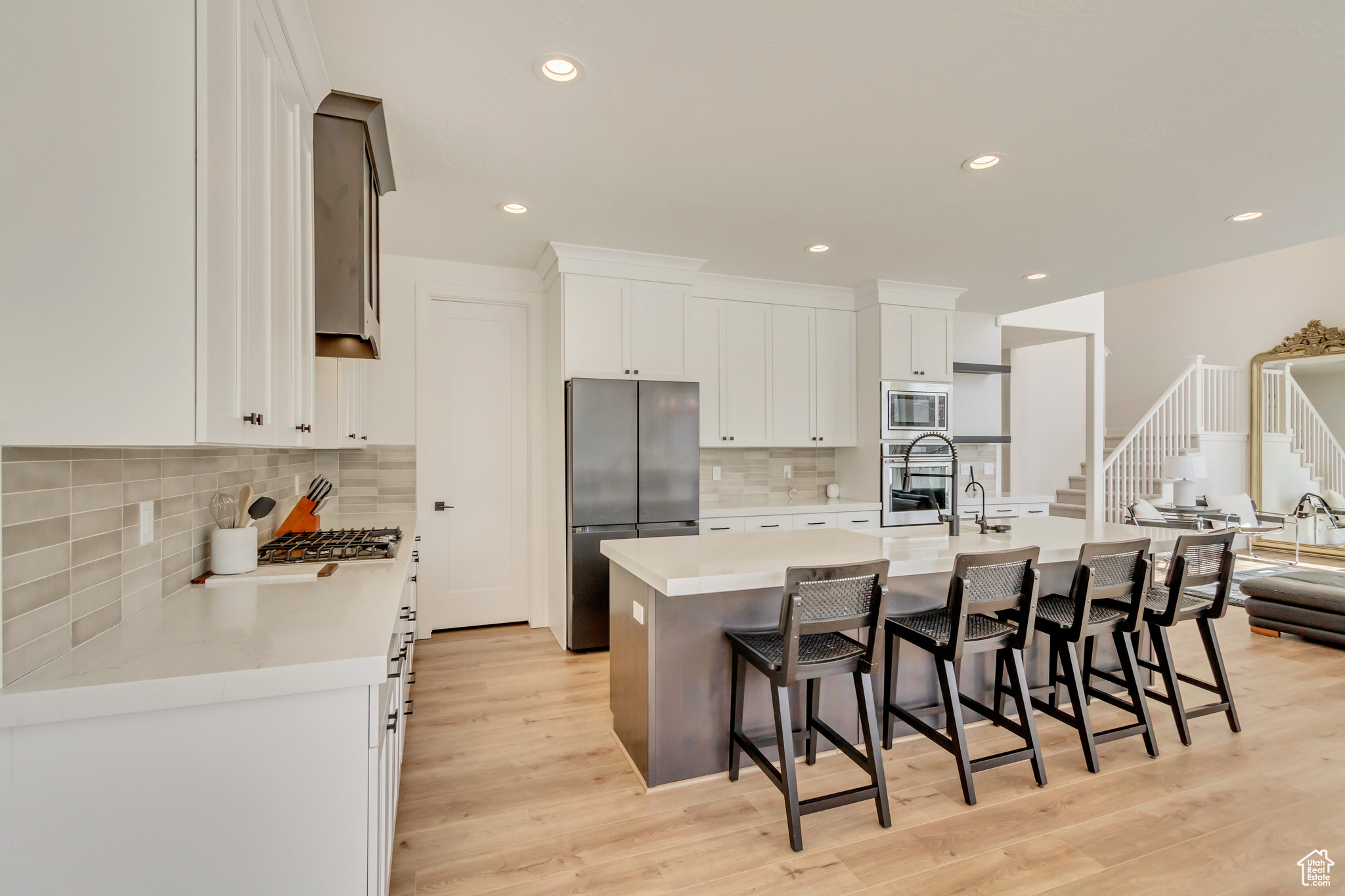 Kitchen with a center island with sink, a breakfast bar, light countertops, white cabinets, and appliances with stainless steel finishes