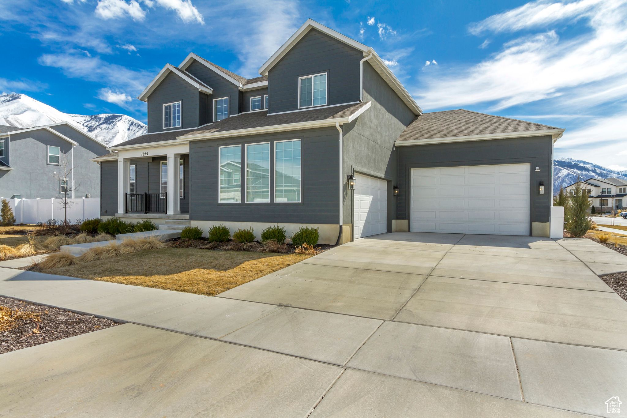 View of front of property featuring fence, driveway, a porch, an attached garage, and a mountain view