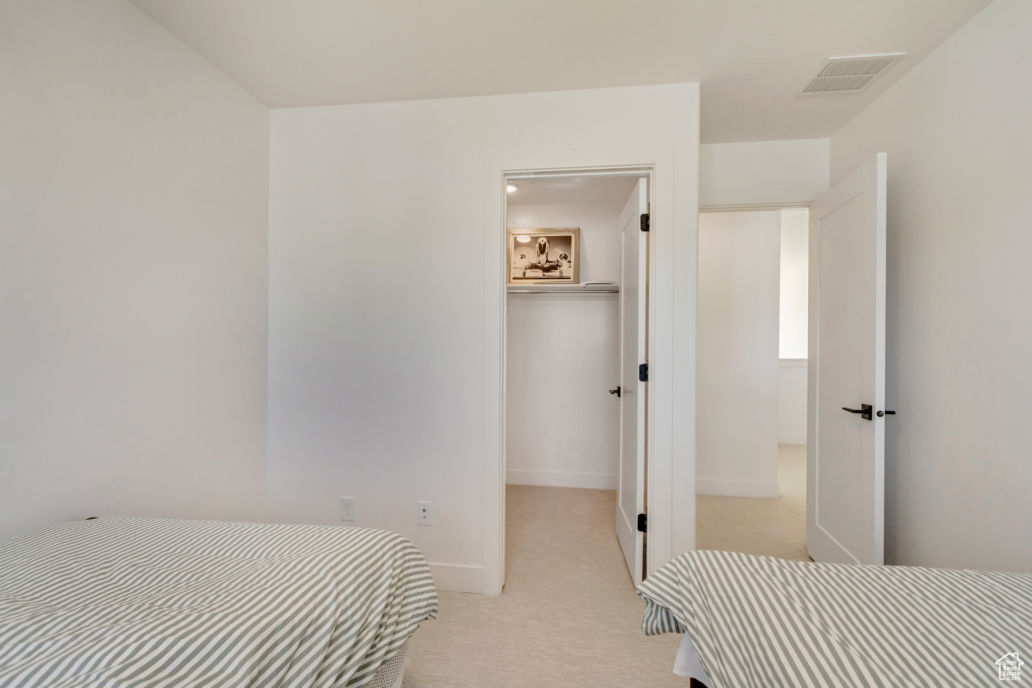 Bedroom featuring baseboards, visible vents, a closet, light carpet, and a walk in closet