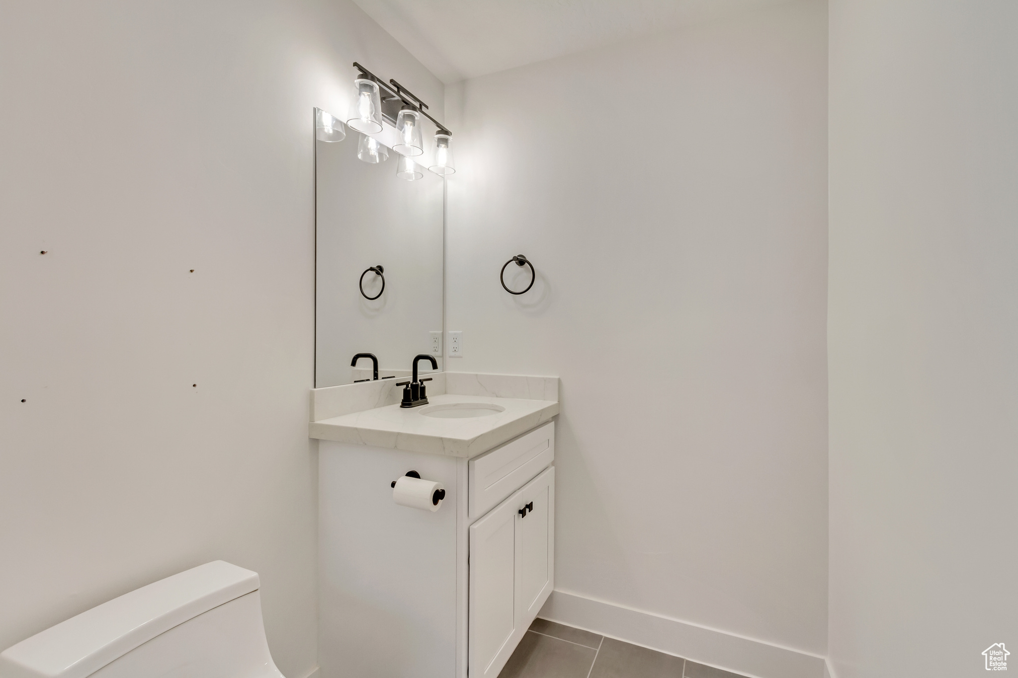 Half bath featuring tile patterned flooring, toilet, vanity, and baseboards