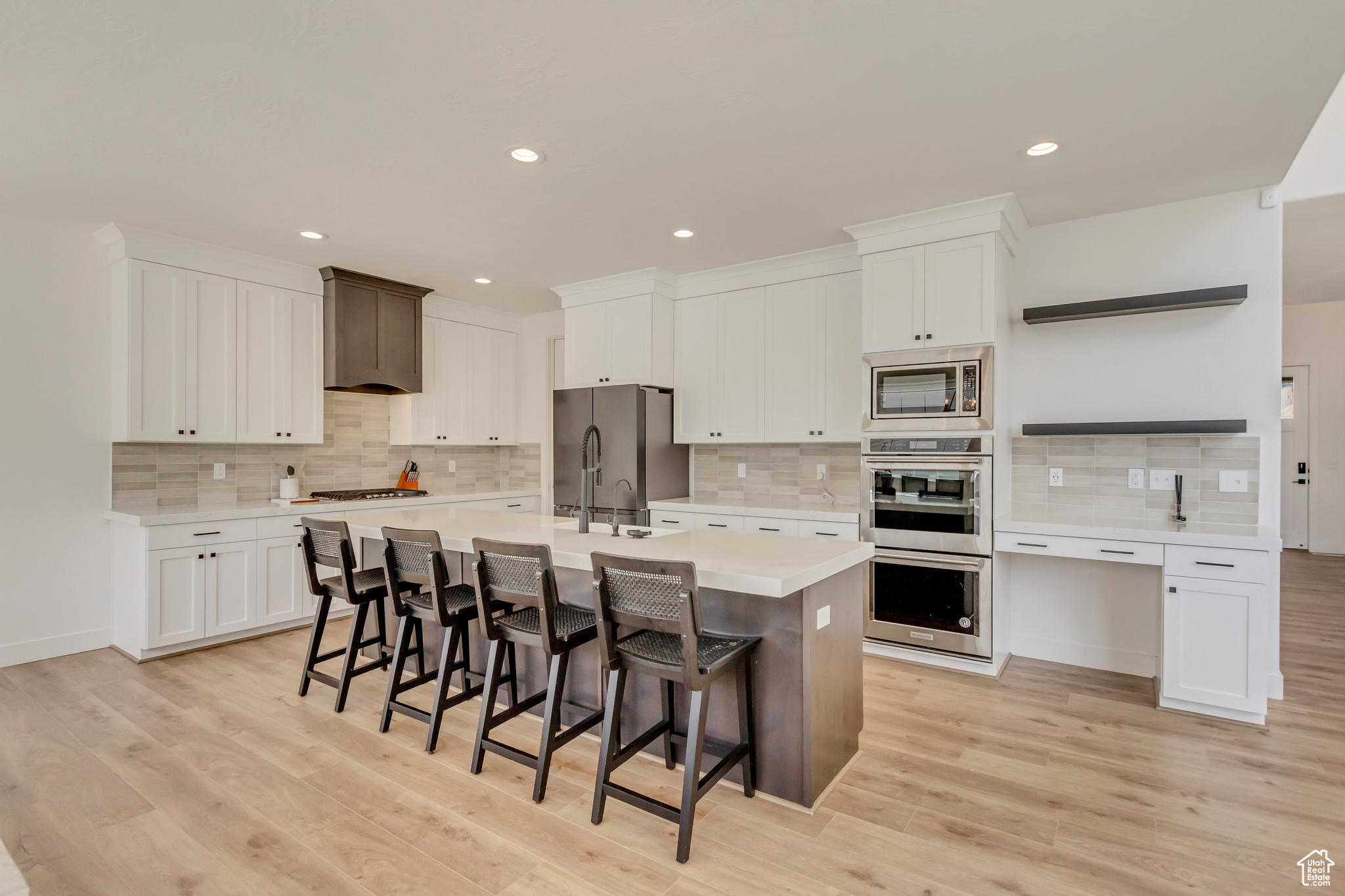 Kitchen with a center island with sink, a breakfast bar area, light countertops, light wood-style floors, and stainless steel appliances