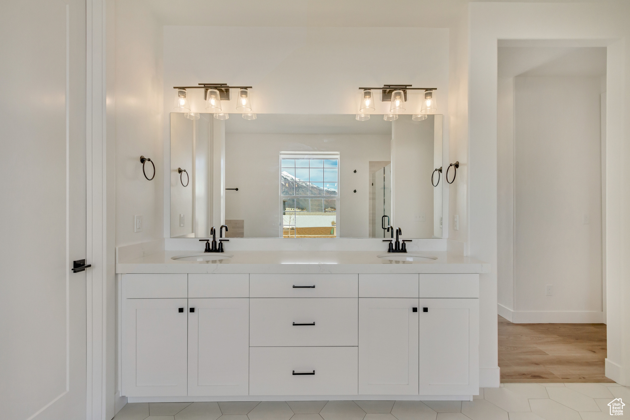 Bathroom featuring a sink, baseboards, a shower with shower door, and double vanity