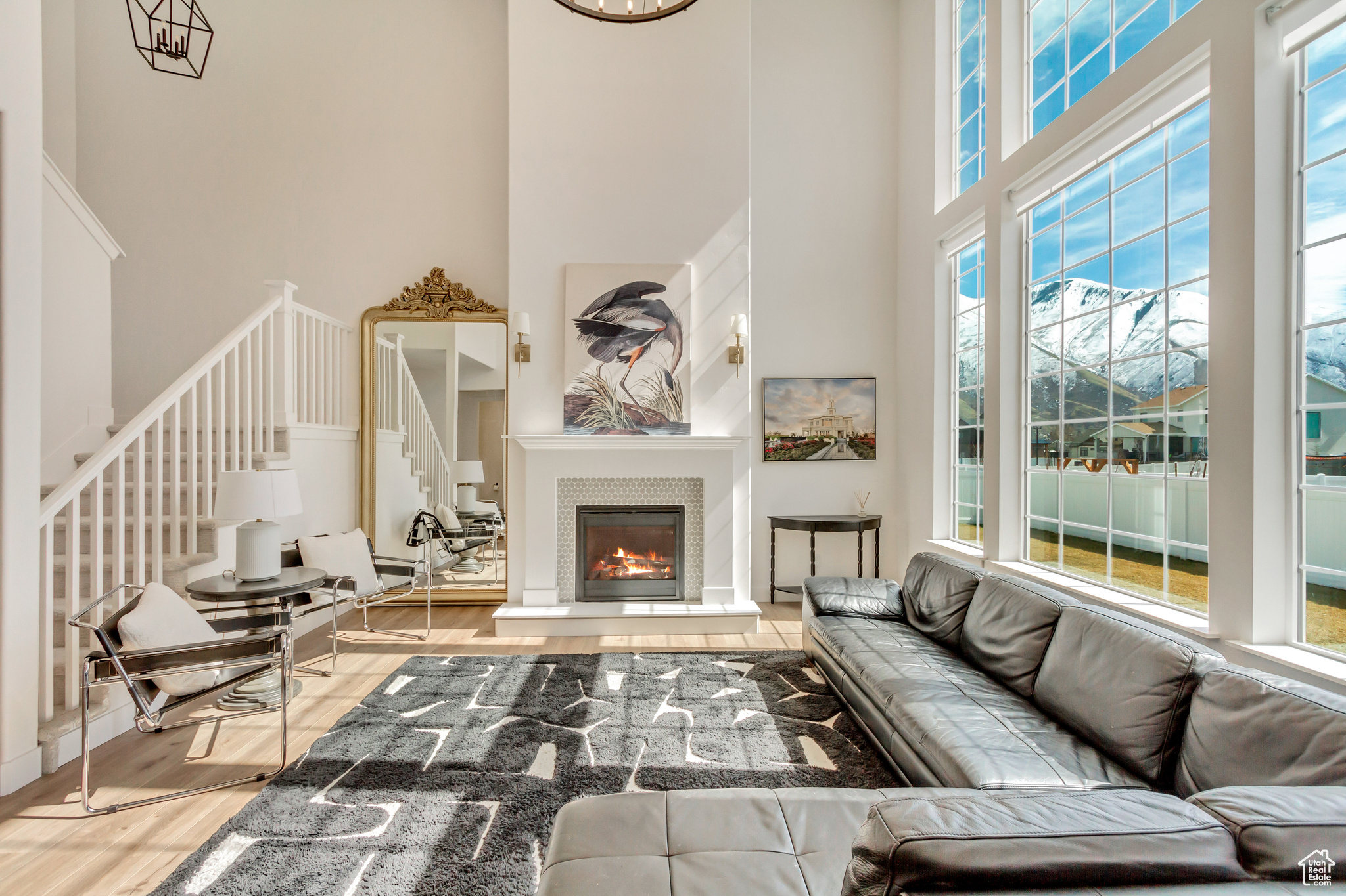 Living room with a fireplace, stairway, wood finished floors, and a towering ceiling