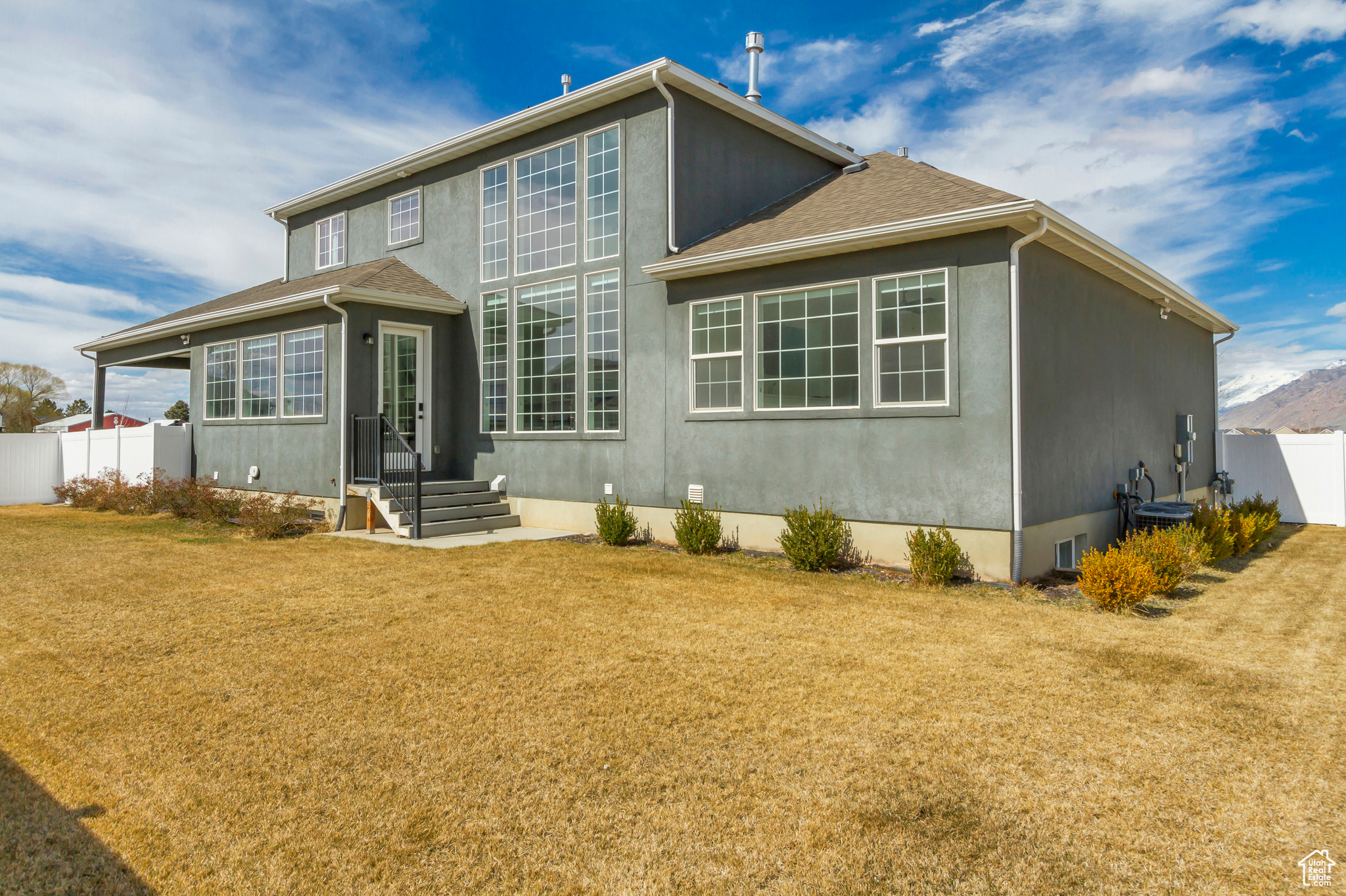 Back of house featuring a yard, cooling unit, stucco siding, and fence