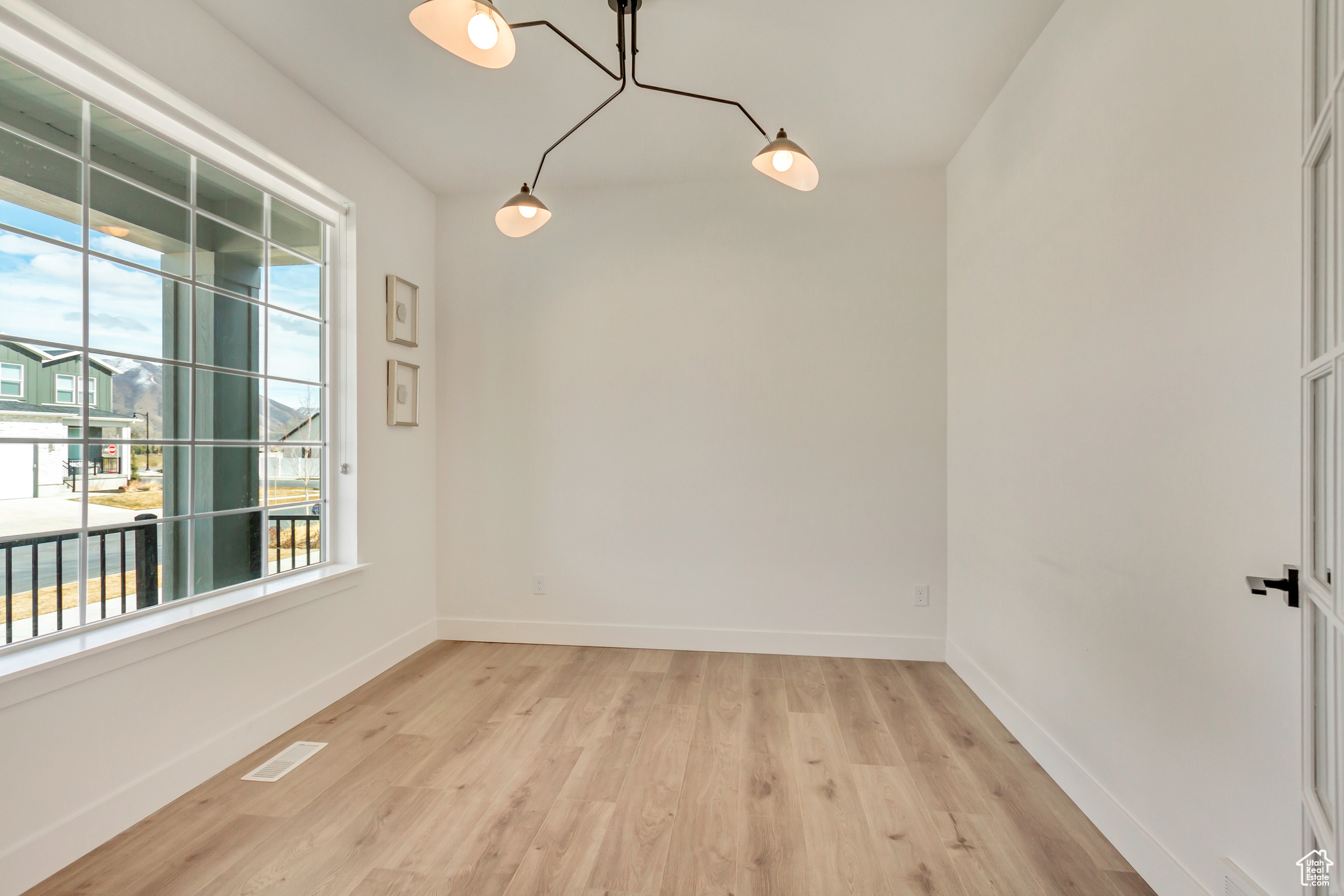 Unfurnished room with visible vents, baseboards, and light wood-style flooring