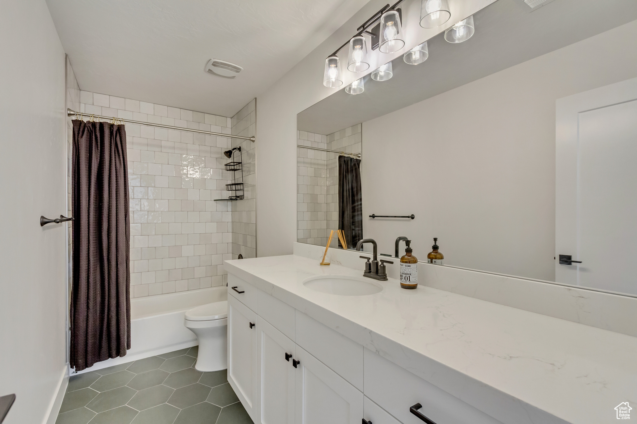 Full bath with vanity, visible vents, shower / bath combo, tile patterned floors, and toilet