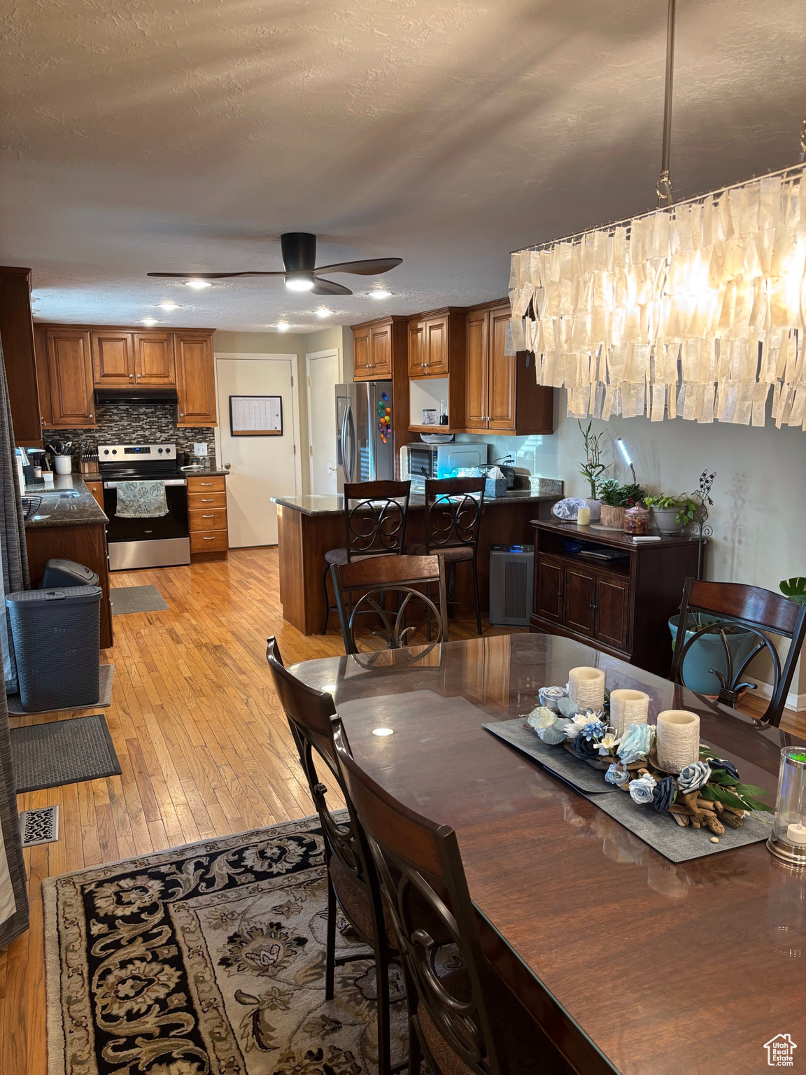 Dining space featuring light wood finished floors, visible vents, a textured ceiling, and ceiling fan