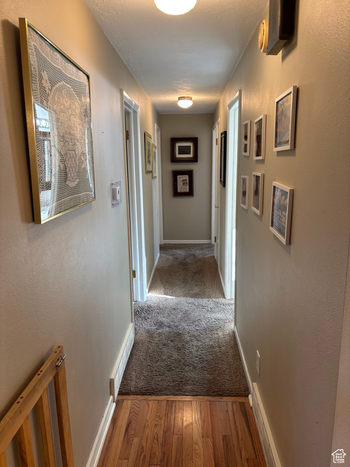 Corridor with a textured ceiling, baseboards, and wood finished floors