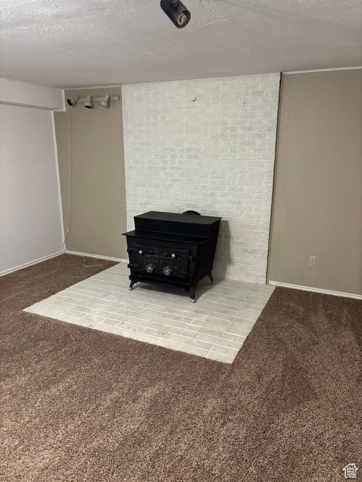 Interior space featuring carpet, a wood stove, and a textured ceiling