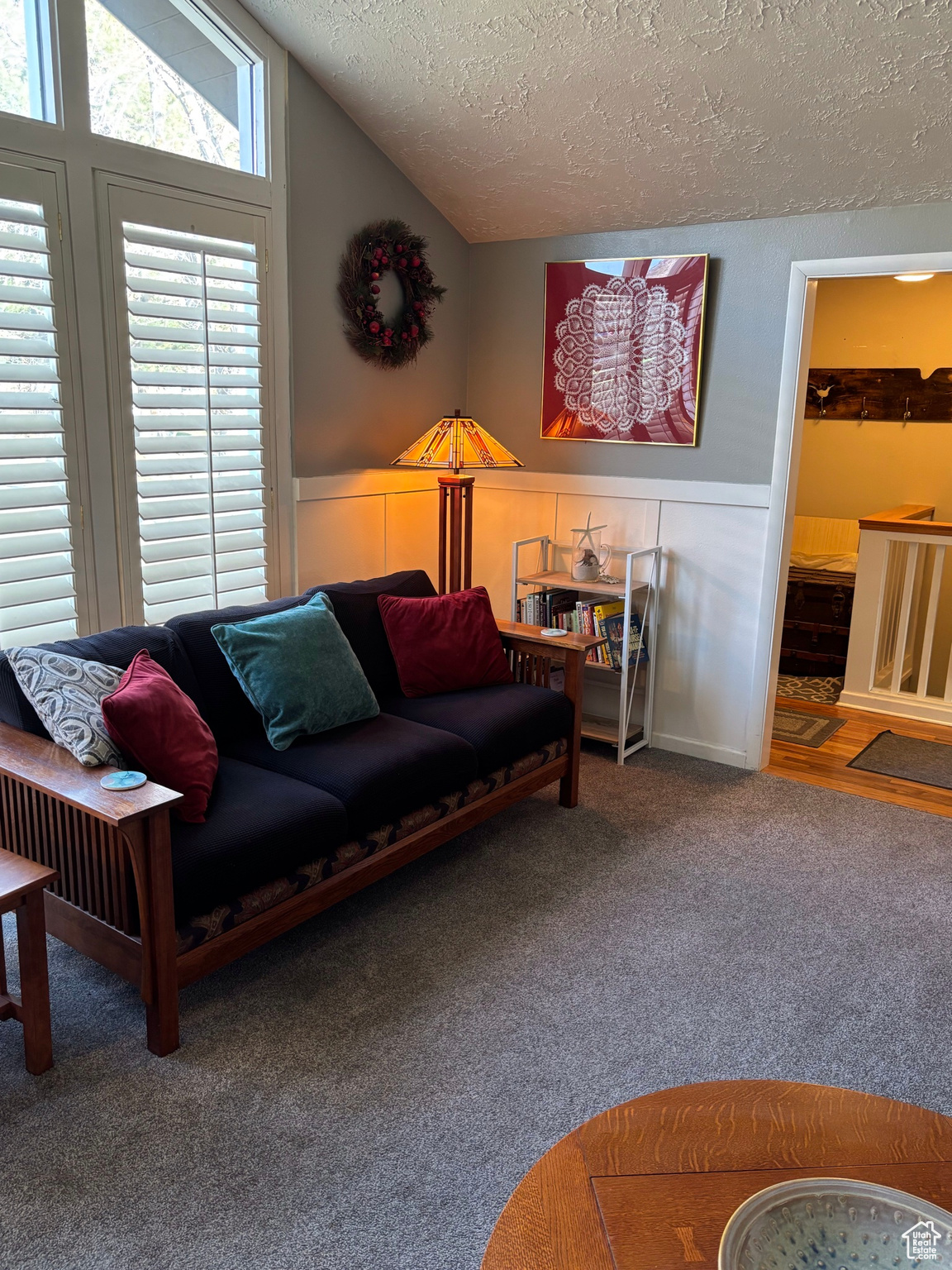 Carpeted living room featuring a textured ceiling and lofted ceiling