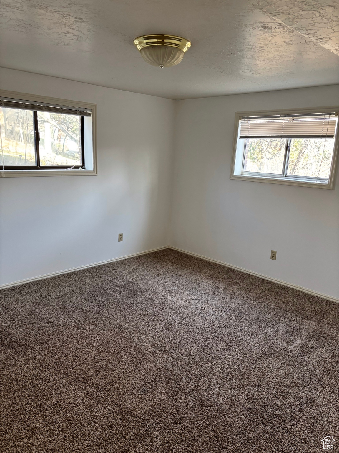 Empty room featuring a textured ceiling, baseboards, and carpet floors