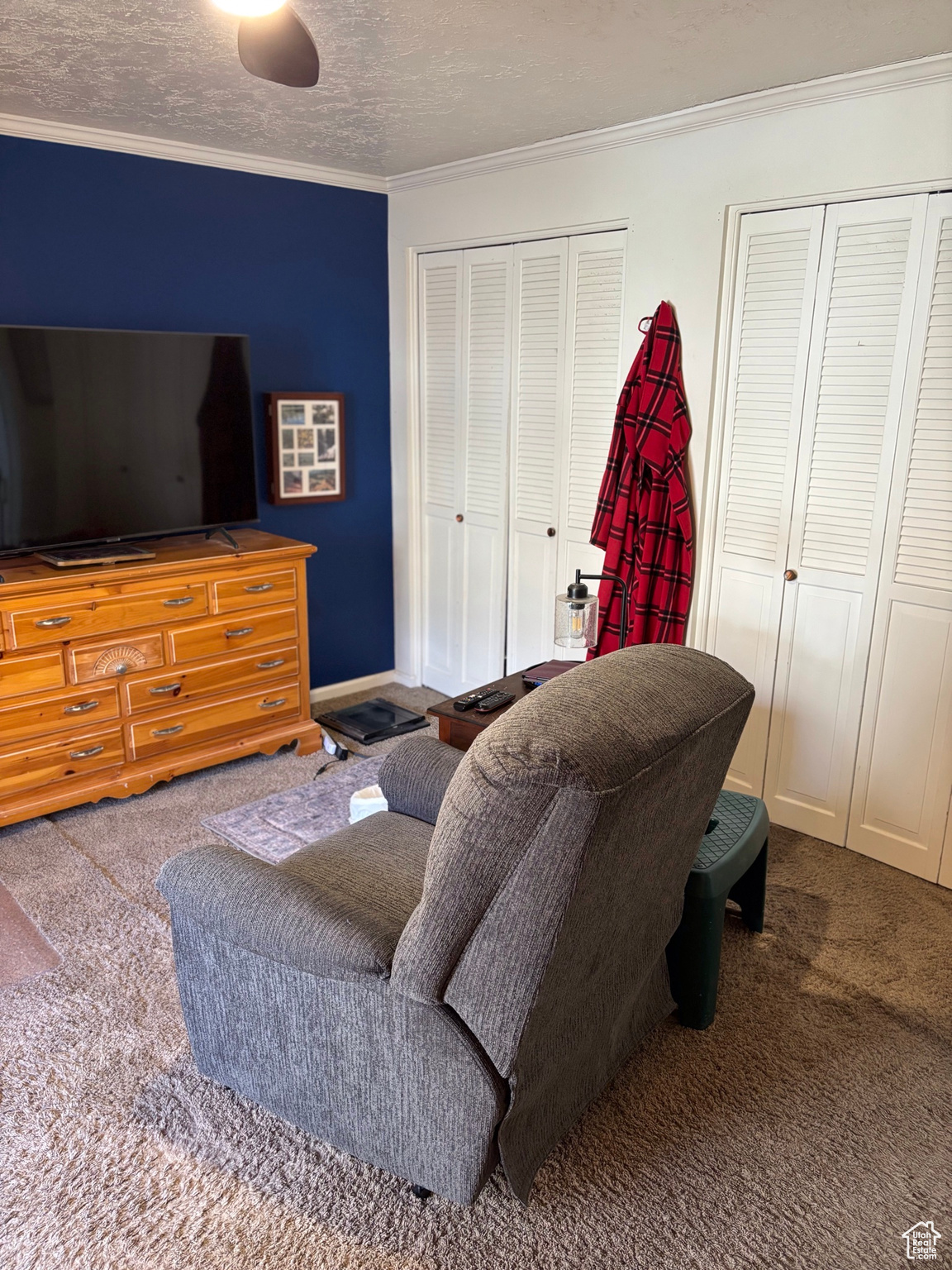 Living area featuring baseboards, a textured ceiling, ornamental molding, and carpet flooring