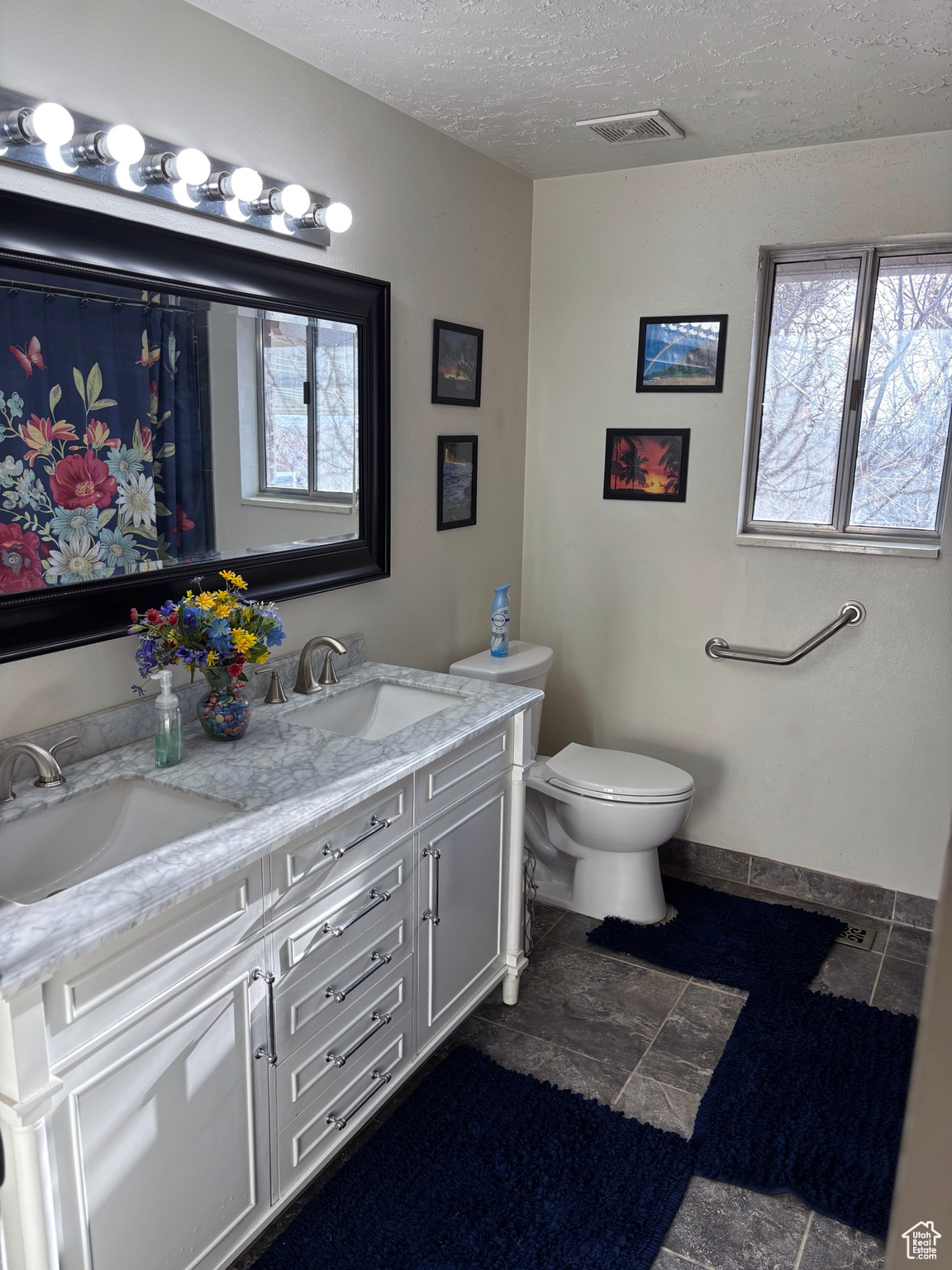 Full bathroom with a sink, visible vents, a textured ceiling, and toilet