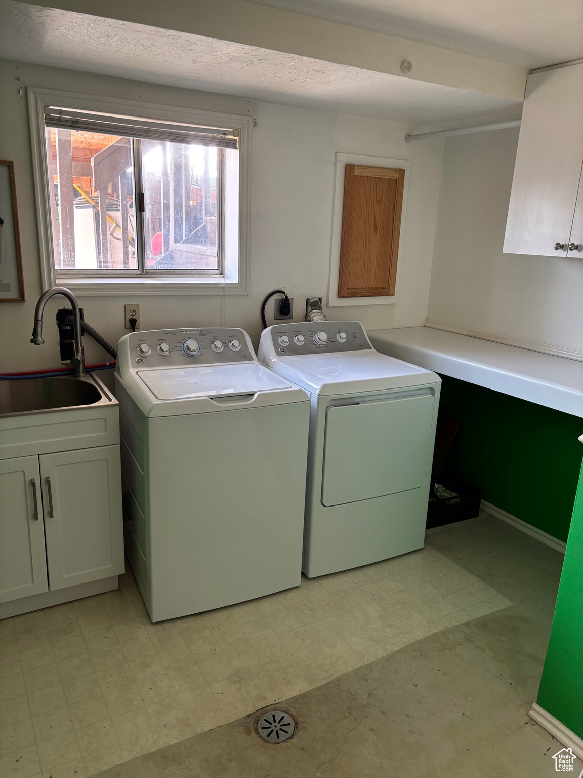 Laundry area featuring cabinet space, washing machine and dryer, light floors, and a sink