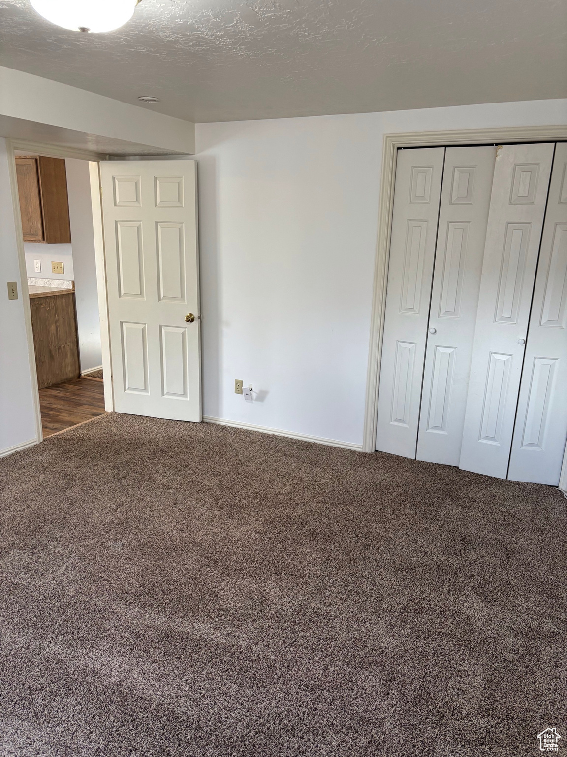 Unfurnished bedroom featuring a closet, a textured ceiling, and carpet