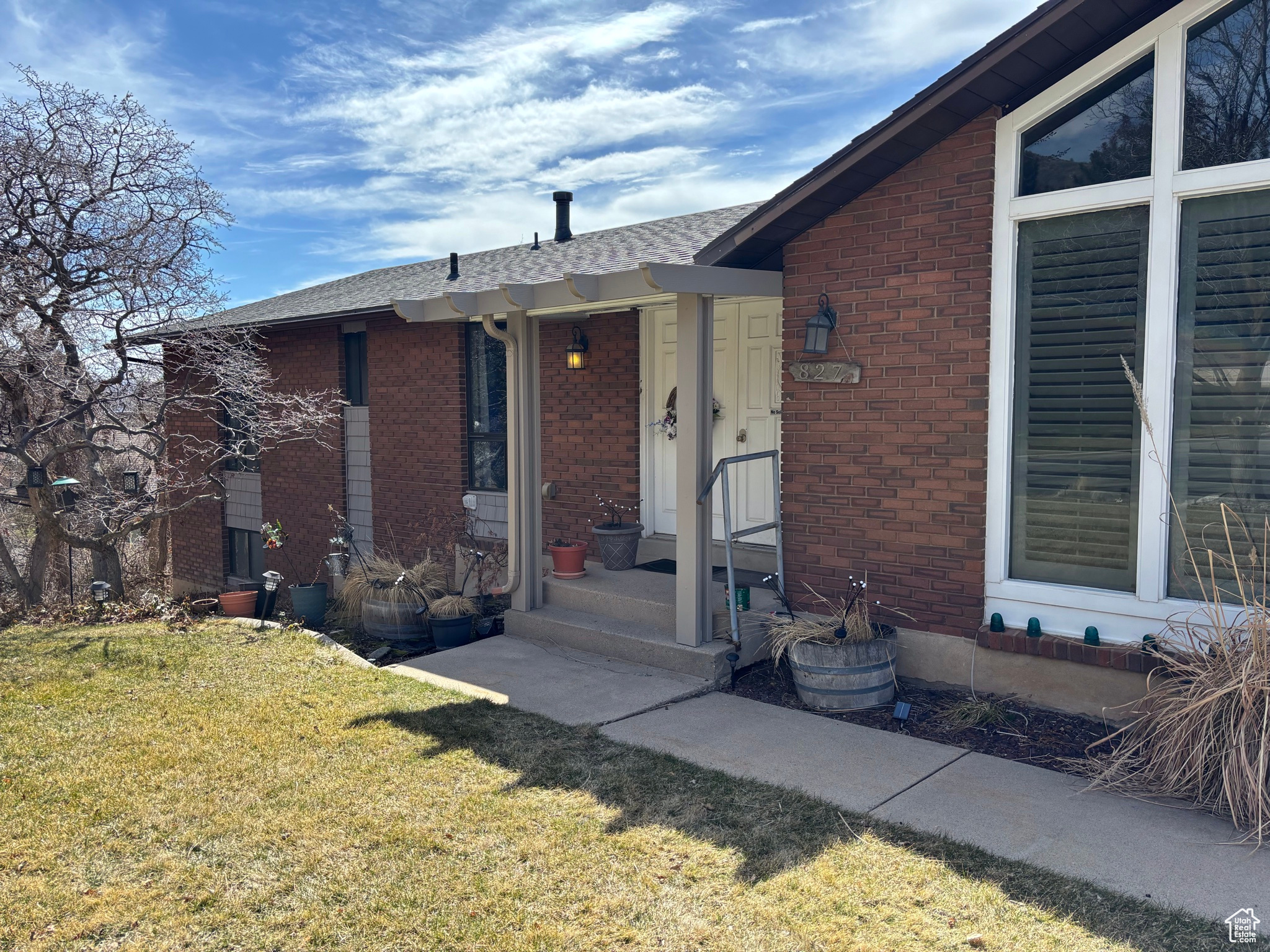 Exterior space featuring brick siding, a shingled roof, and a front lawn