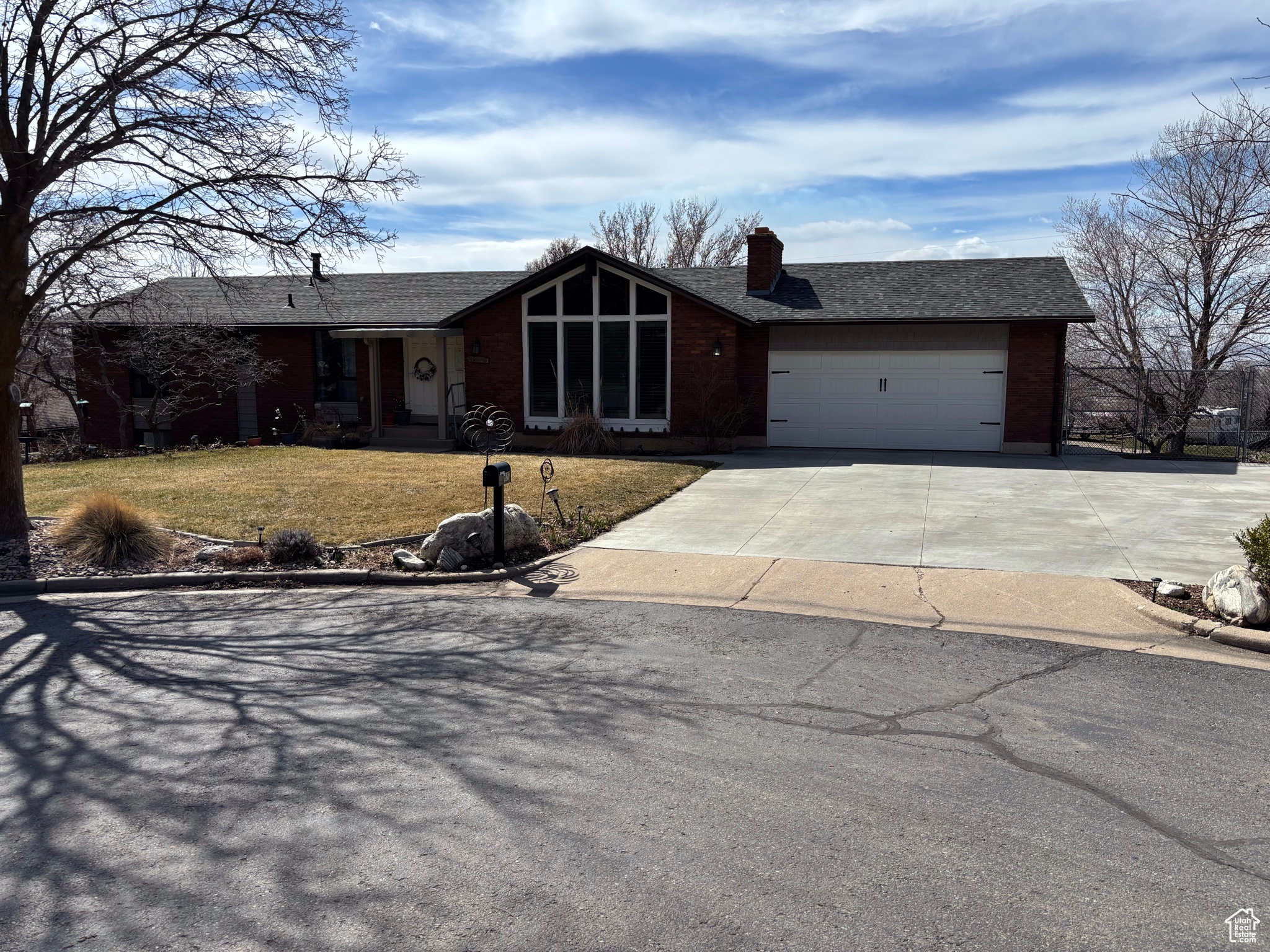 View of front of home featuring roof with shingles, concrete driveway, a front yard, an attached garage, and a chimney