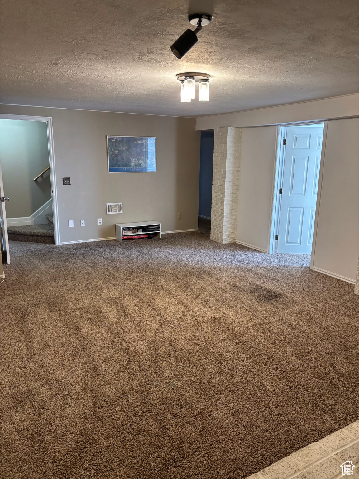 Spare room with baseboards, visible vents, carpet floors, and a textured ceiling