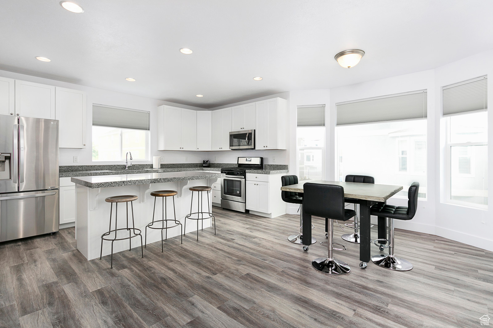 Kitchen featuring a kitchen breakfast bar, a kitchen island, white cabinets, and stainless steel appliances