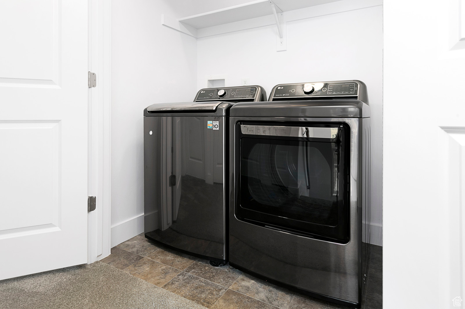 Washroom with washer and clothes dryer, laundry area, stone finish floor, and baseboards