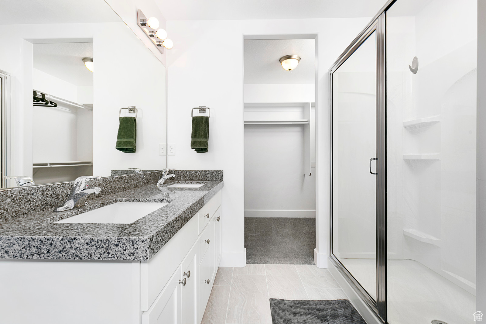 Full bathroom with a spacious closet, a stall shower, double vanity, and a sink