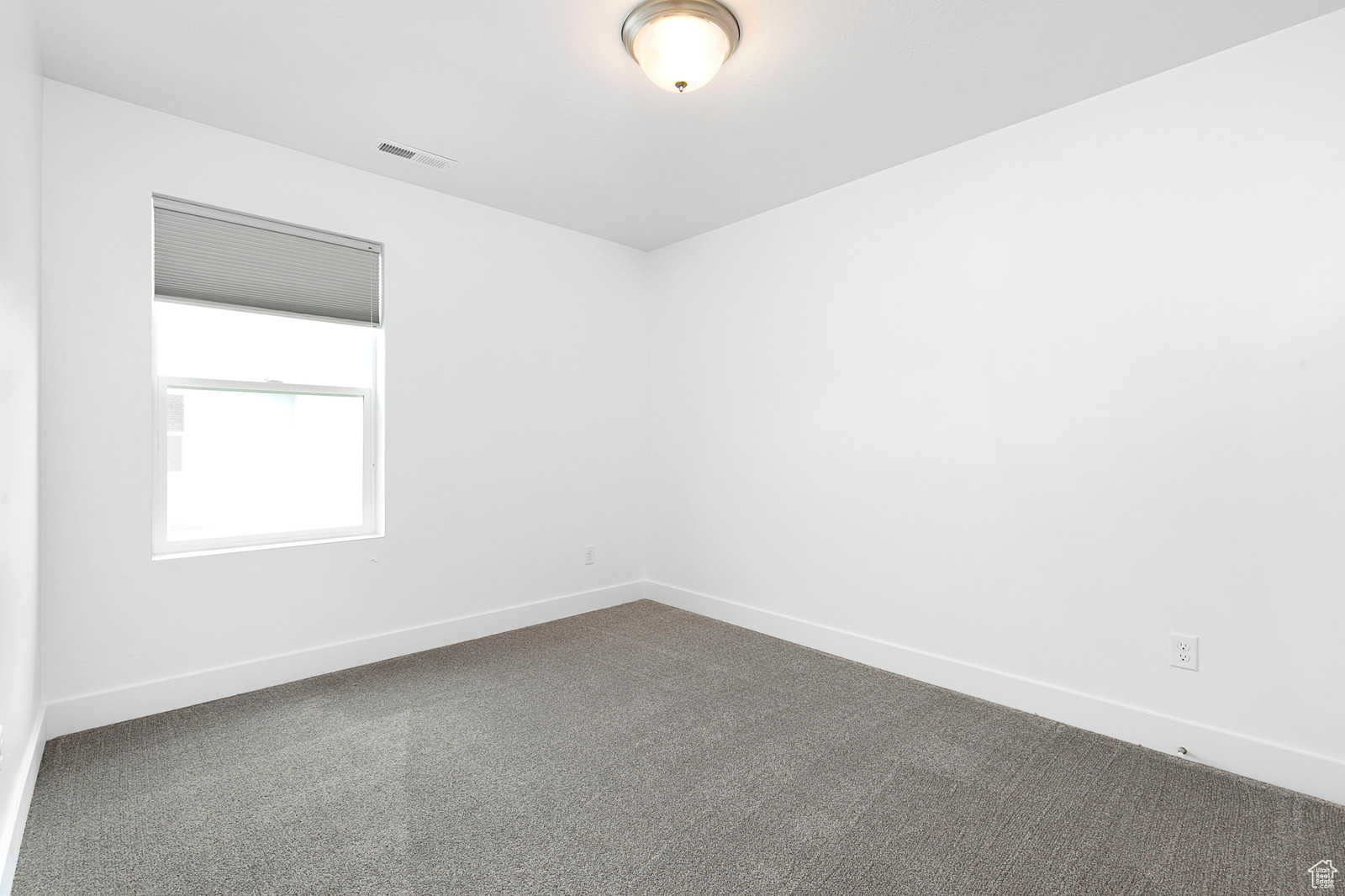 Unfurnished room featuring baseboards, visible vents, and dark carpet