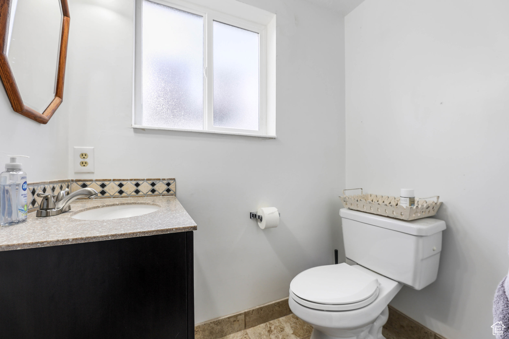 Bathroom featuring baseboards, toilet, and vanity