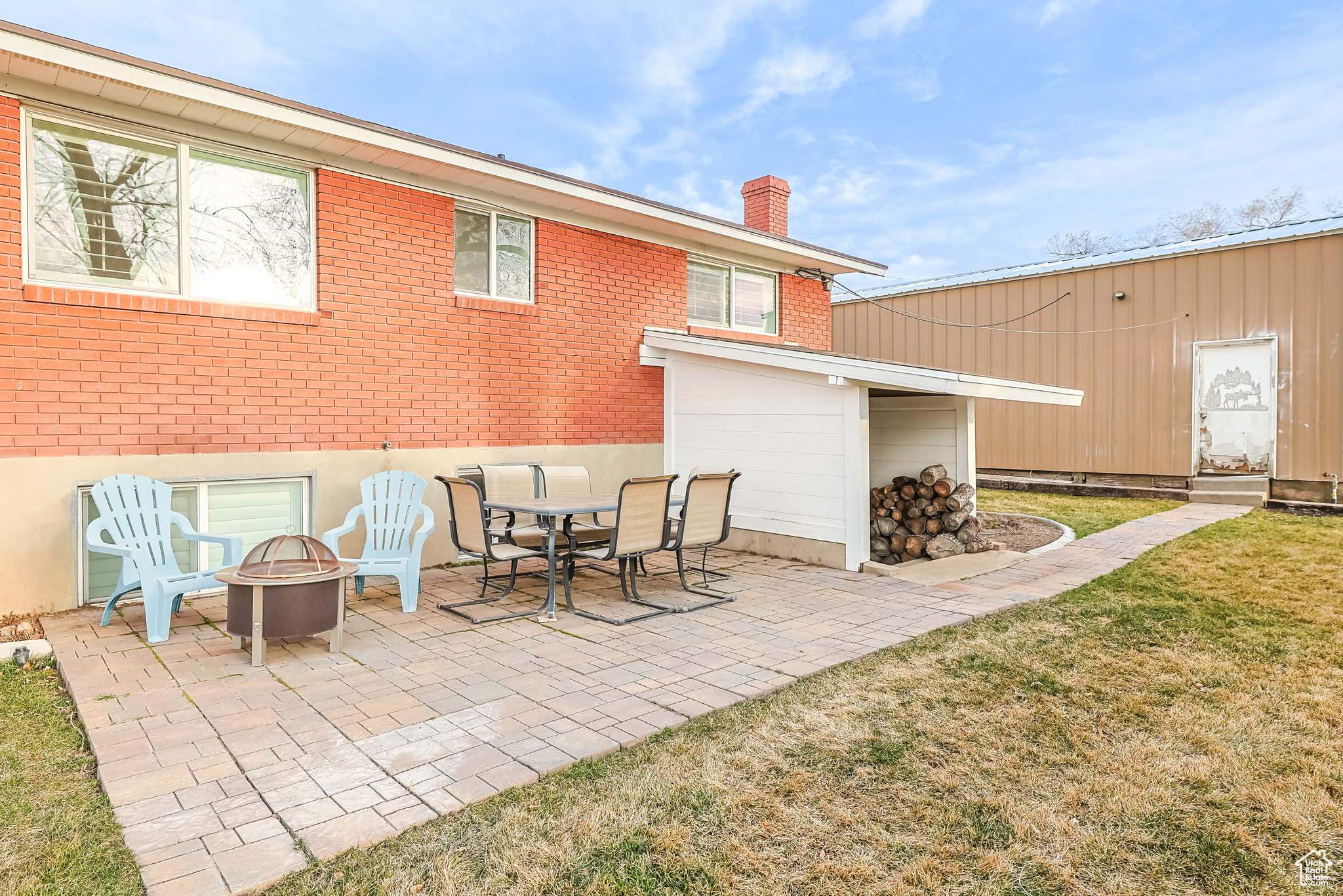 Back of house featuring a yard, a patio, brick siding, and a chimney