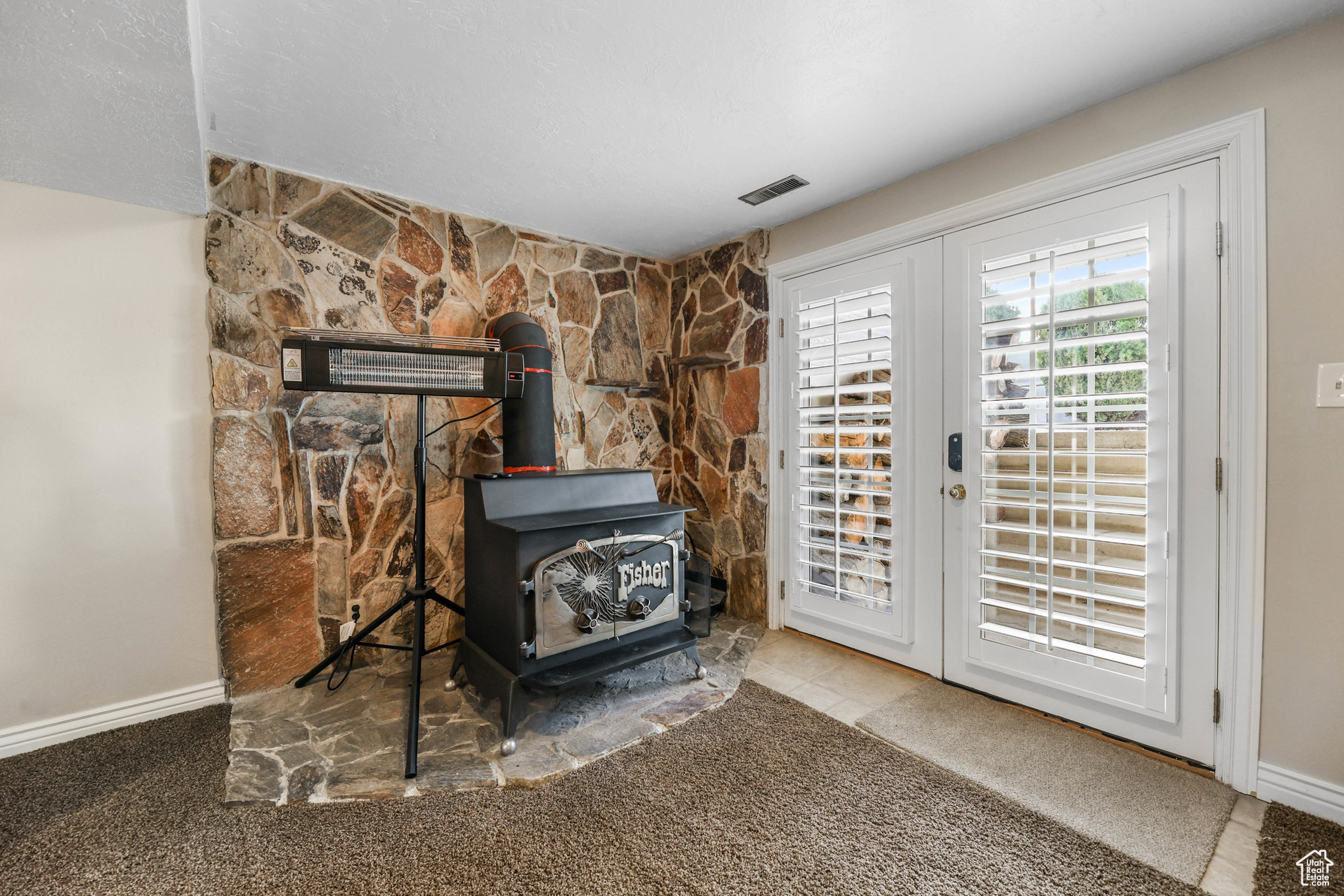 Room details with french doors, baseboards, carpet floors, and a wood stove