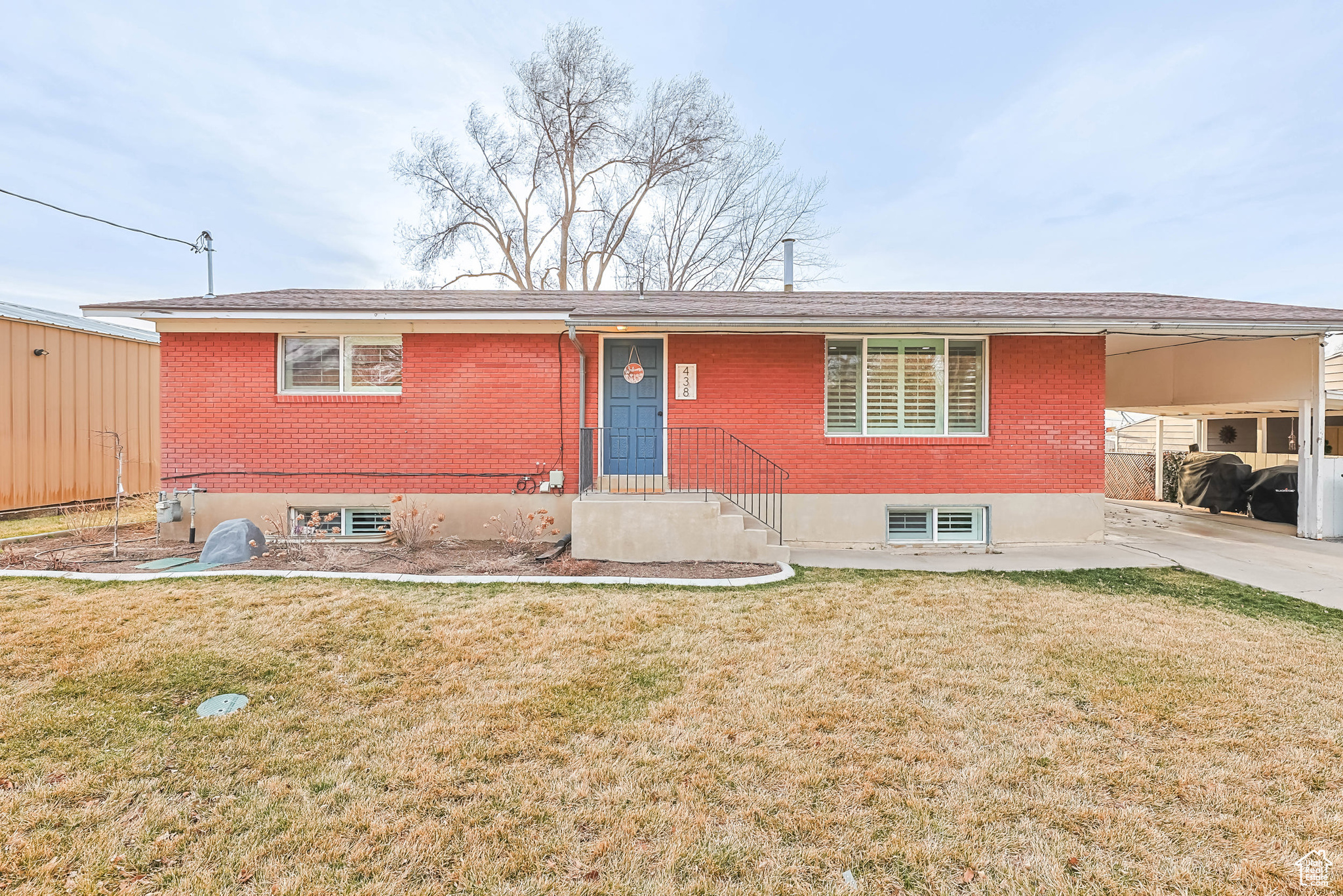 Single story home featuring brick siding, a front yard, and a carport