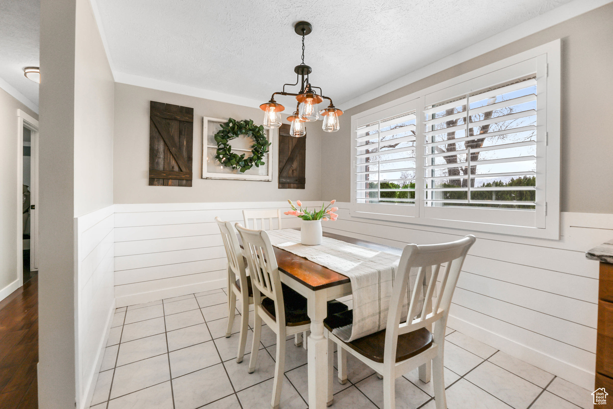 Dining area with a wainscoted wall, a textured ceiling, a chandelier, and wooden walls