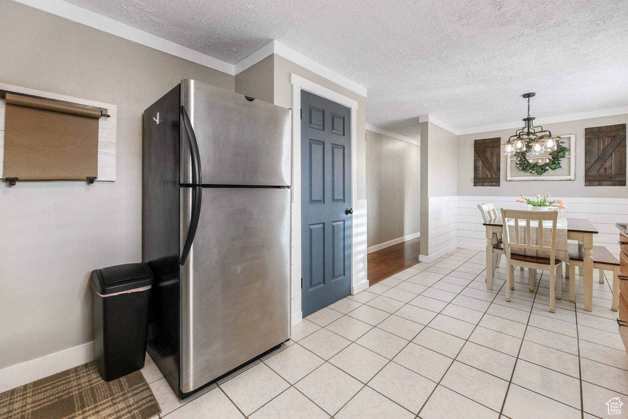 Kitchen featuring a chandelier, light tile patterned flooring, freestanding refrigerator, and a textured ceiling