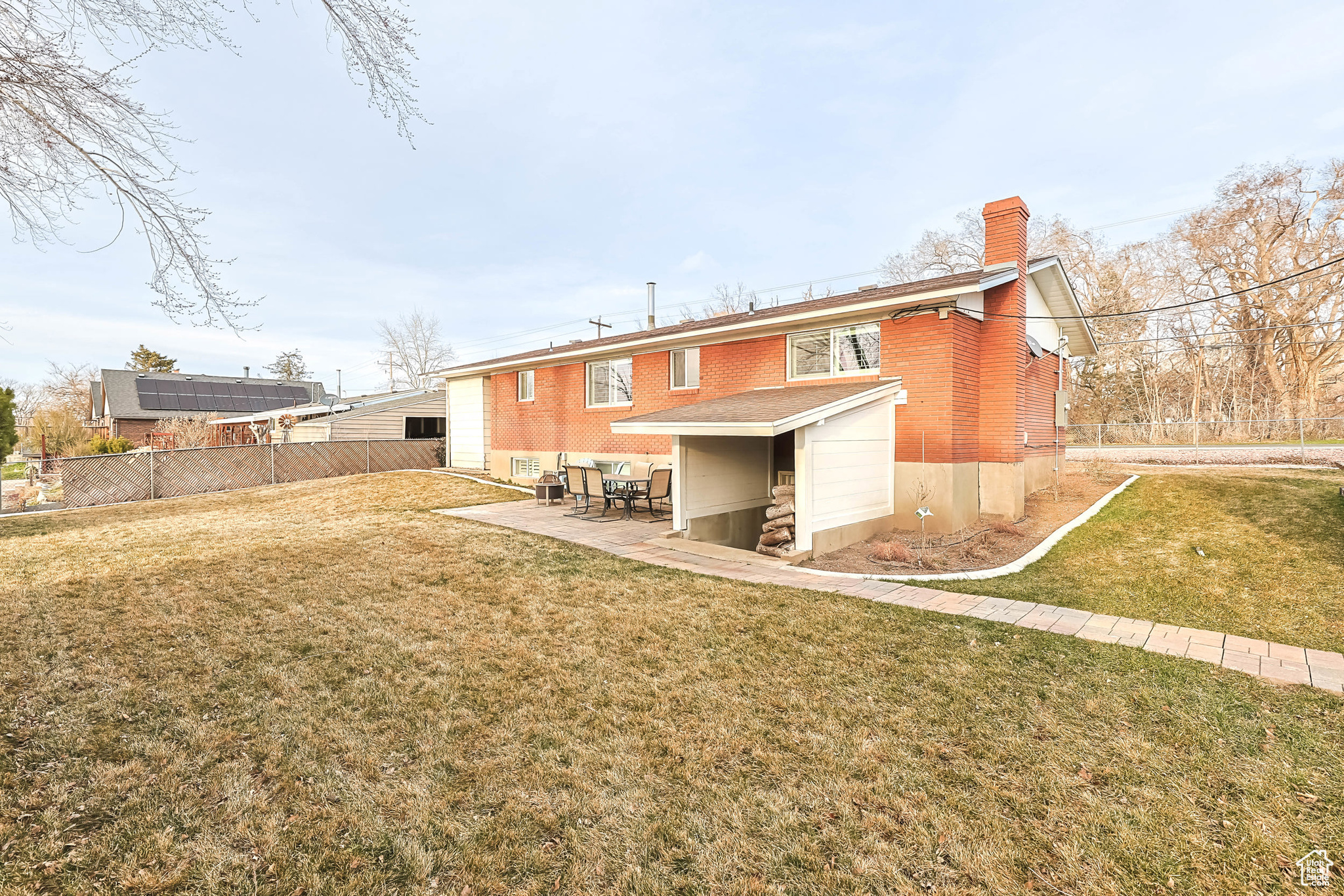 Rear view of property with brick siding, fence, a chimney, a yard, and a patio area