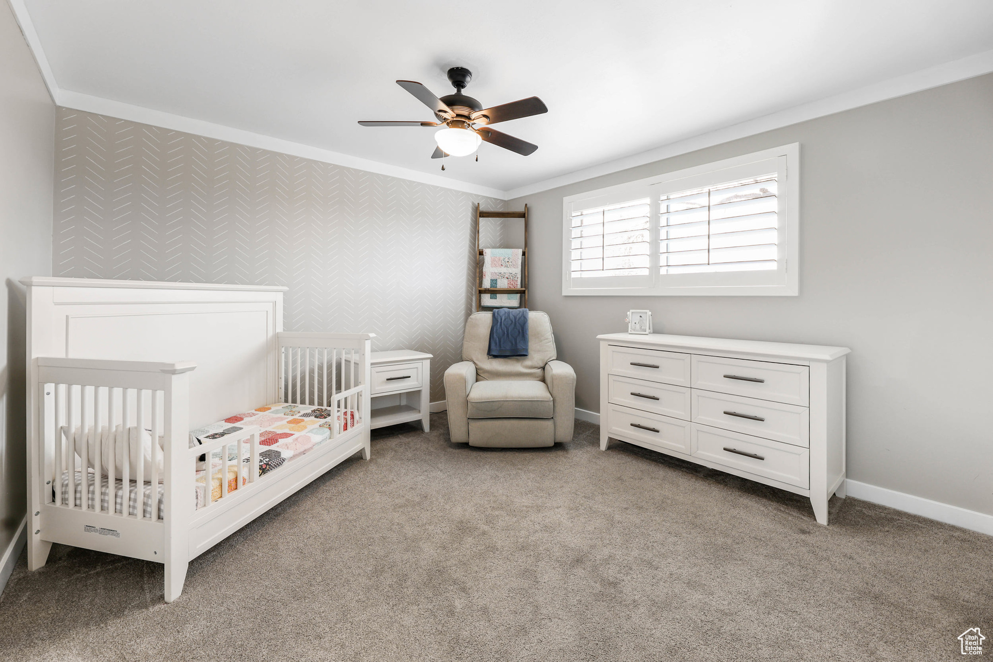 Bedroom featuring baseboards, ceiling fan, a crib, ornamental molding, and light carpet