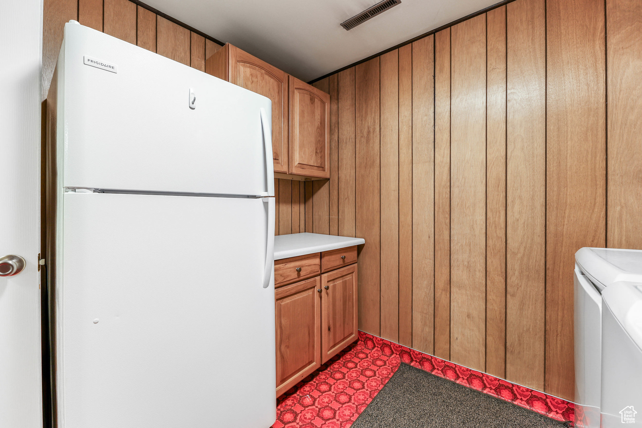 Washroom featuring wooden walls, visible vents, washing machine and clothes dryer, cabinet space, and tile patterned floors