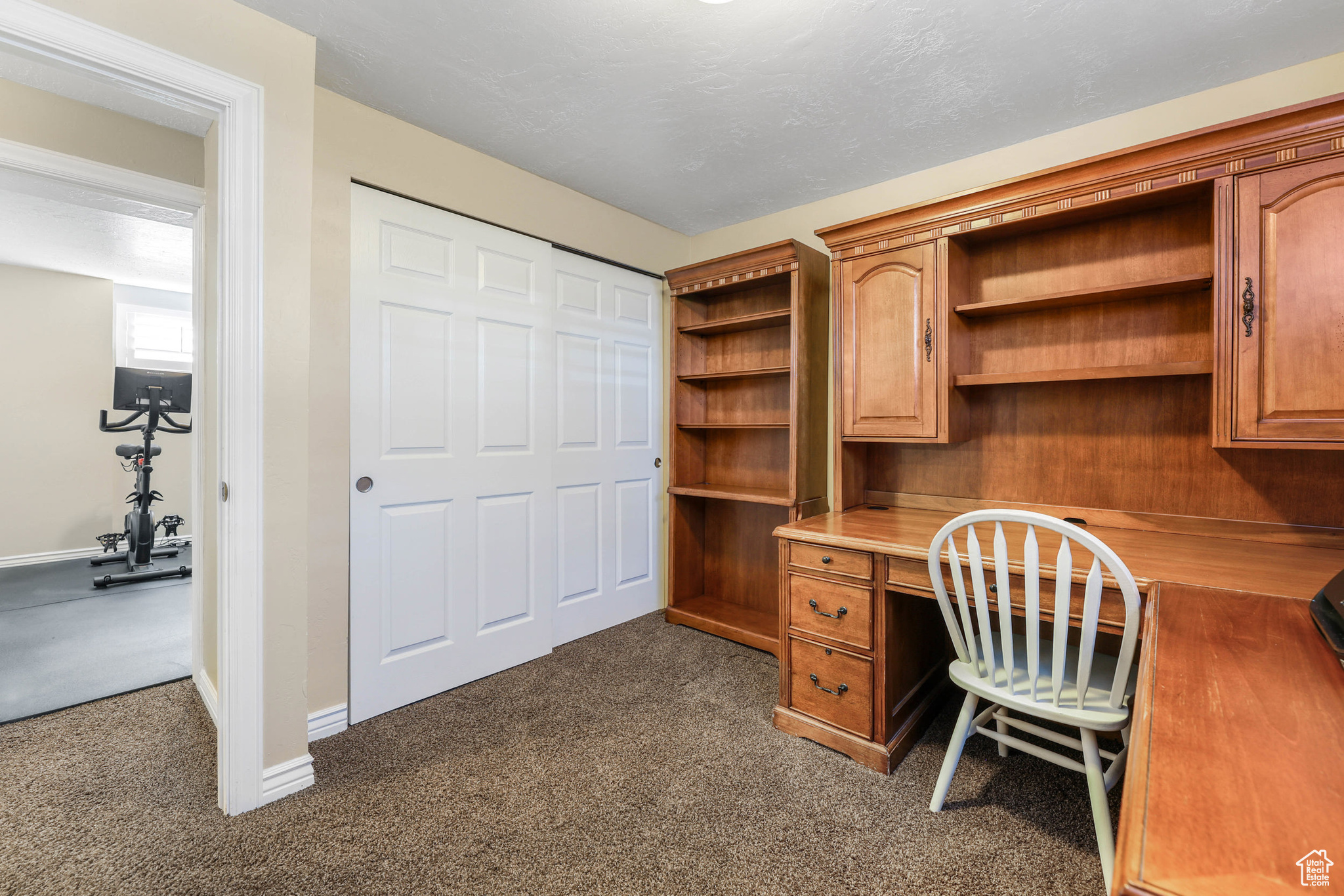 Office space featuring dark colored carpet, baseboards, and built in desk