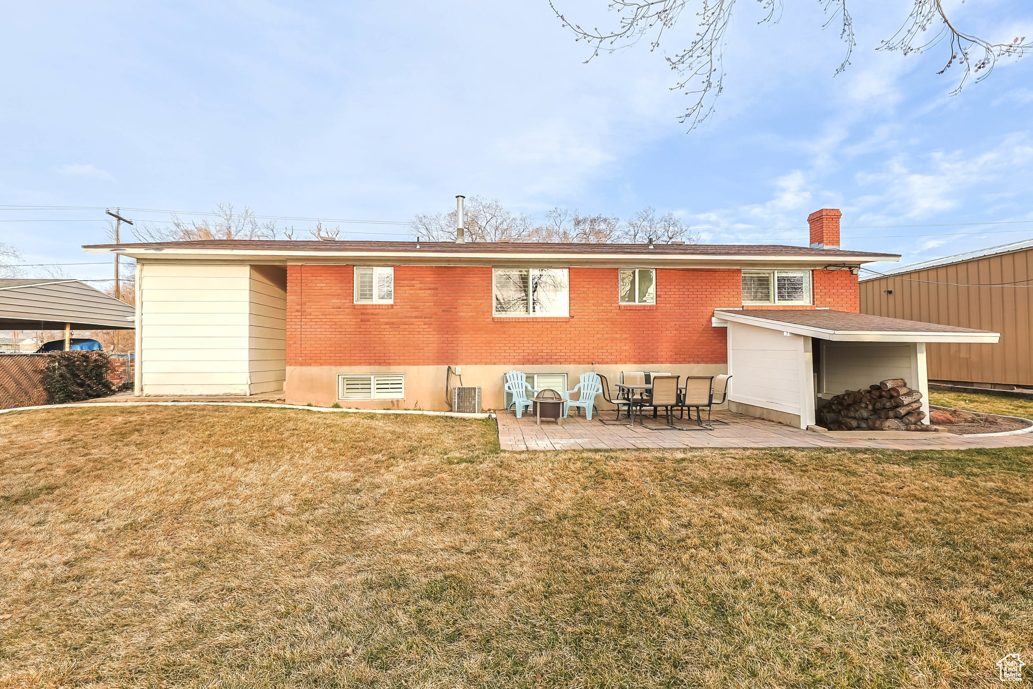 Rear view of house featuring a patio, a lawn, and brick siding