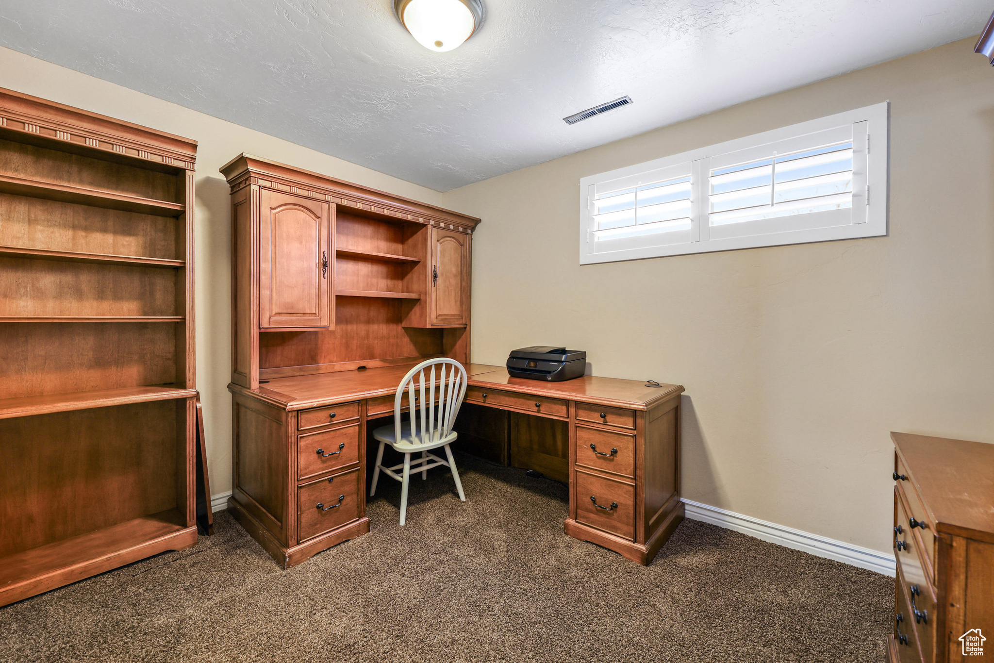 Office space featuring visible vents, a textured ceiling, baseboards, and dark colored carpet