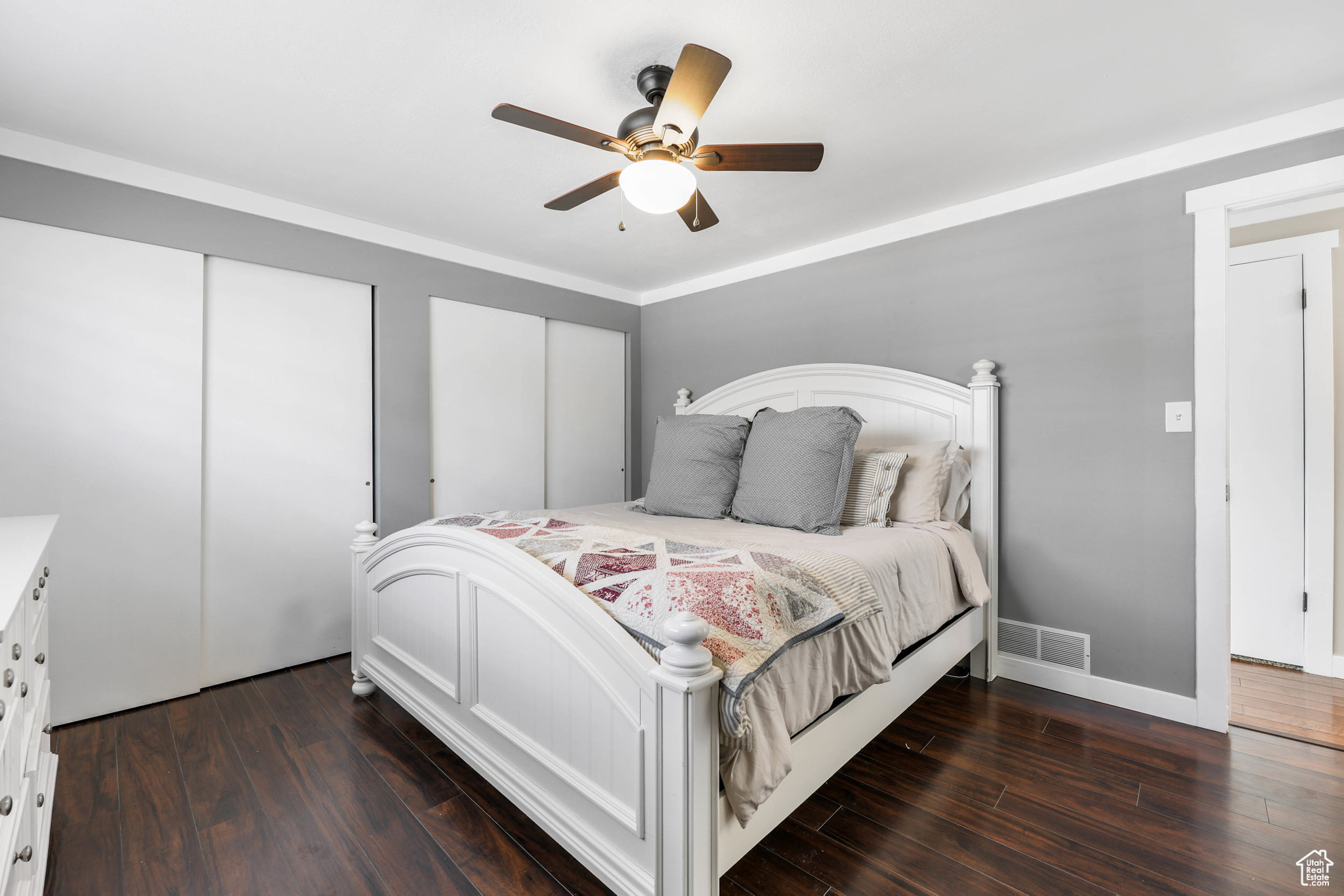 Bedroom with baseboards, visible vents, dark wood-style flooring, ceiling fan, and multiple closets