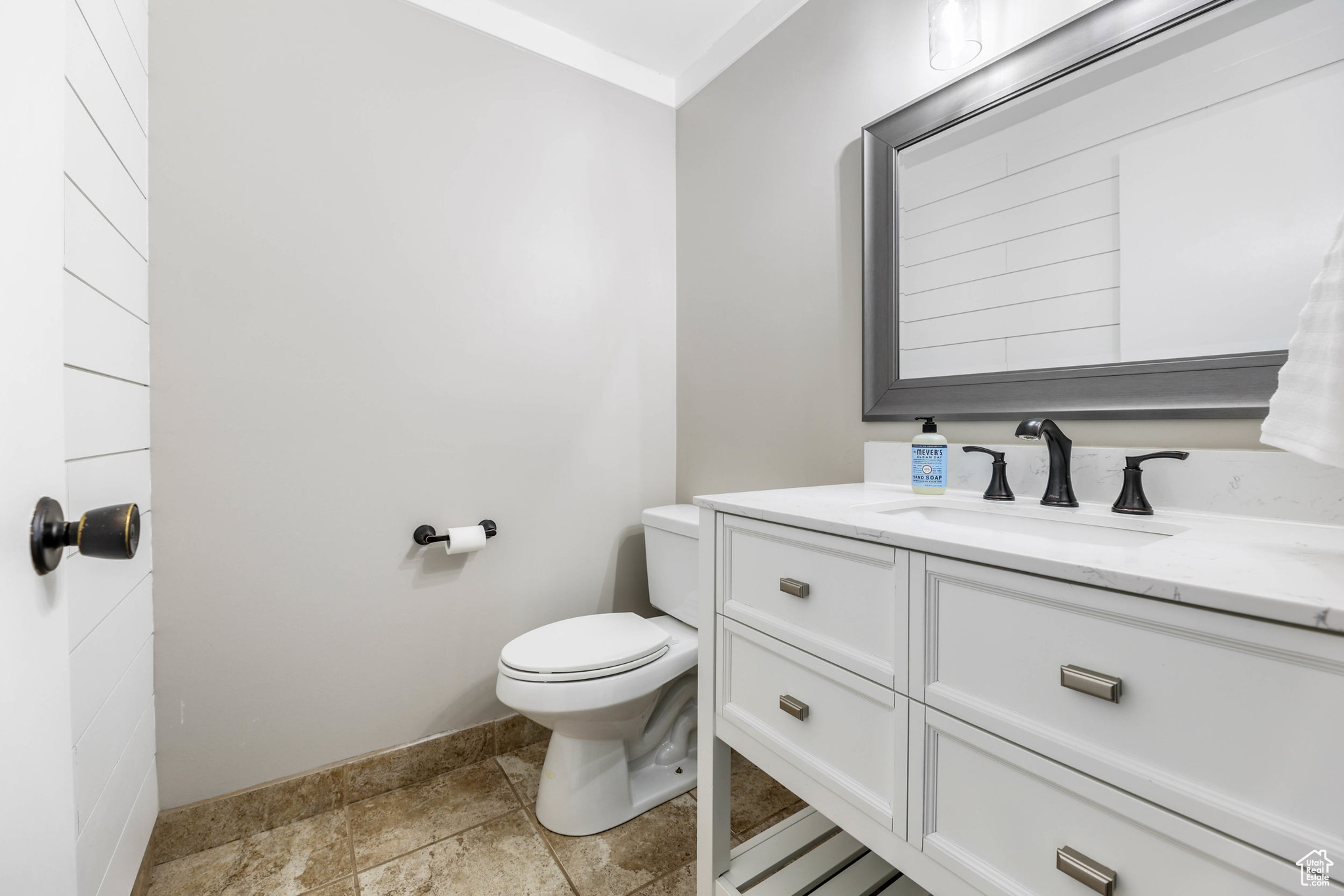 Bathroom with stone finish flooring, toilet, and vanity