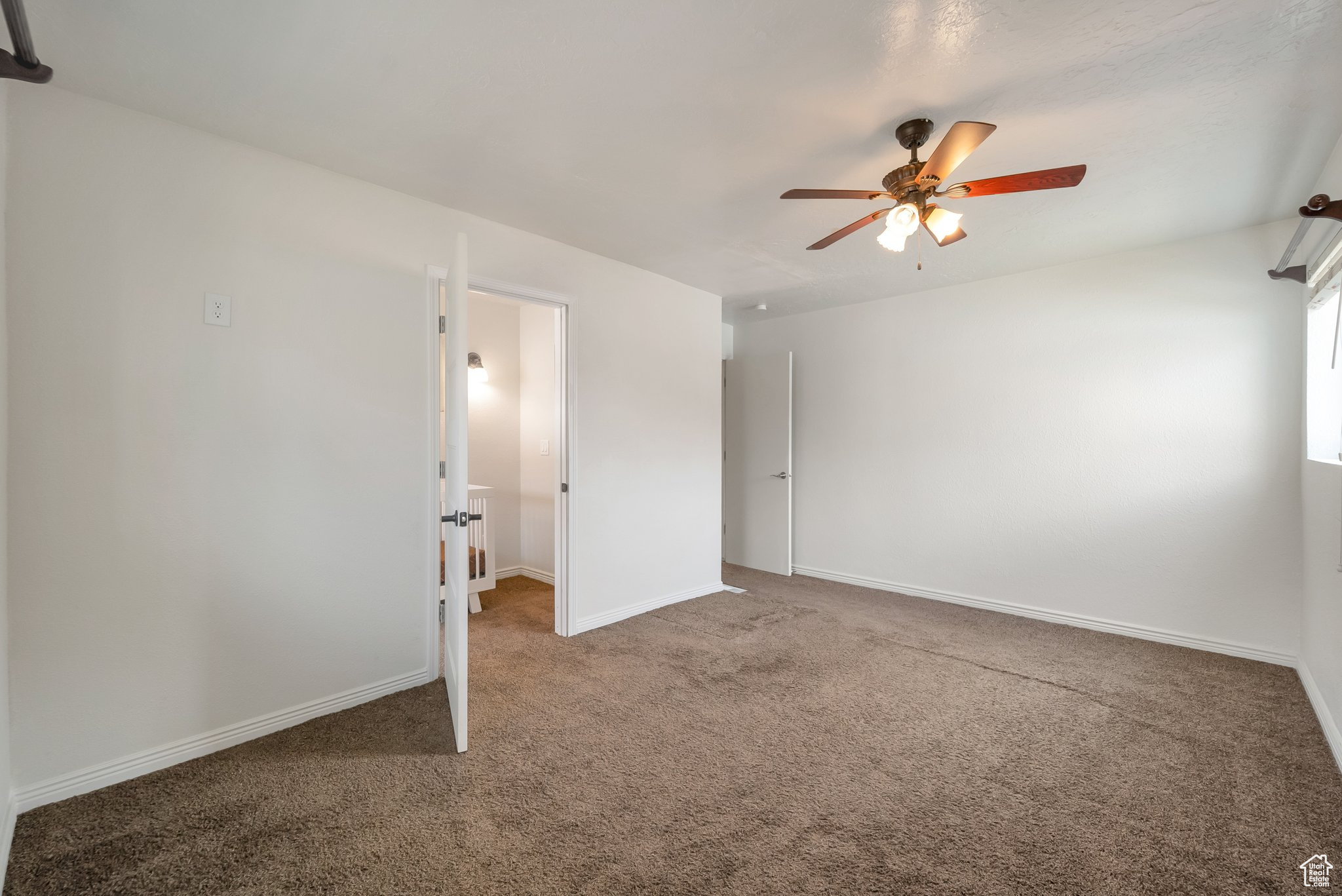 Carpeted spare room featuring baseboards and a ceiling fan